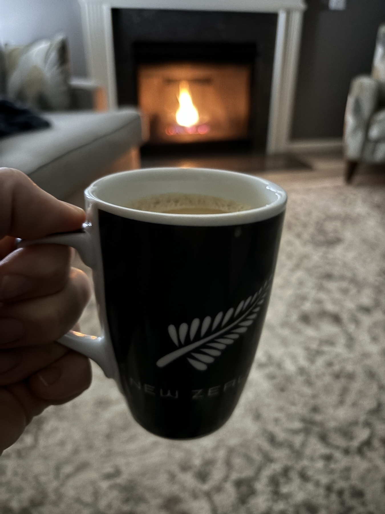 An All Blacks mug in front of a fireplace. 