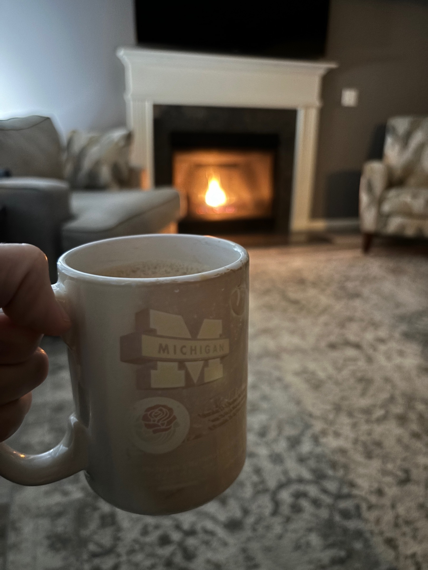 Coffee mug in front of an inviting fireplace. 