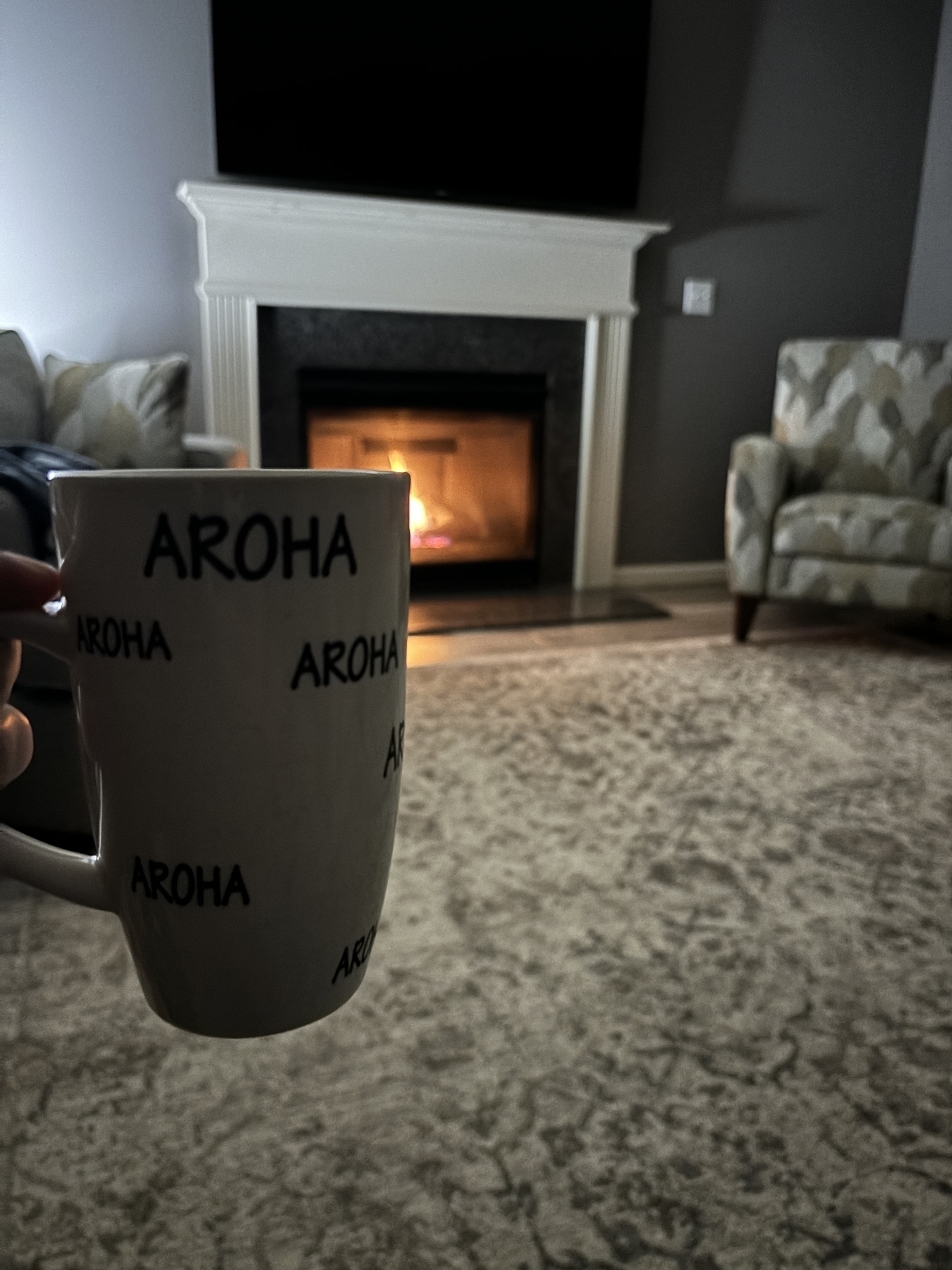 A mug with the Māori word, “Aroha,” which means love in front of an inviting fire