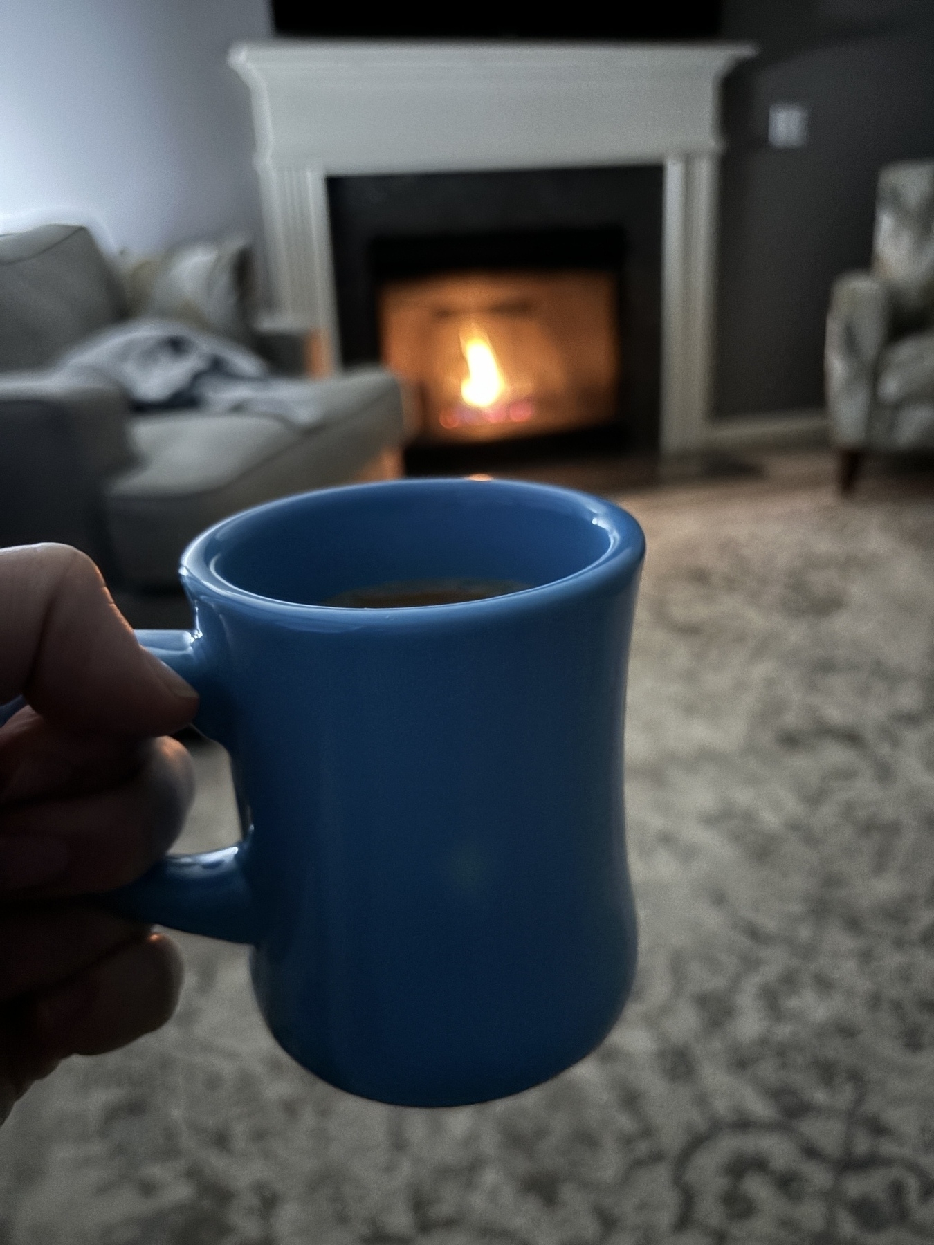 A light blue mug in front of a fireplace