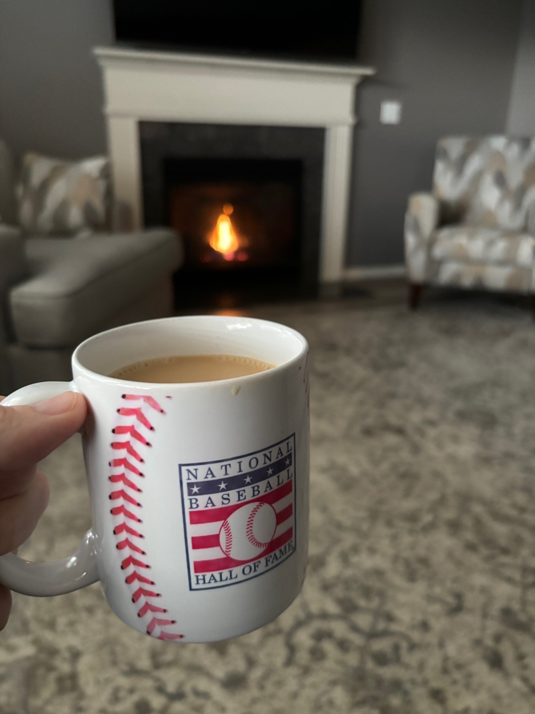 A national baseball hall of fame coffee mug filled with glorious Guatemalan coffee in front of a fireplace. 