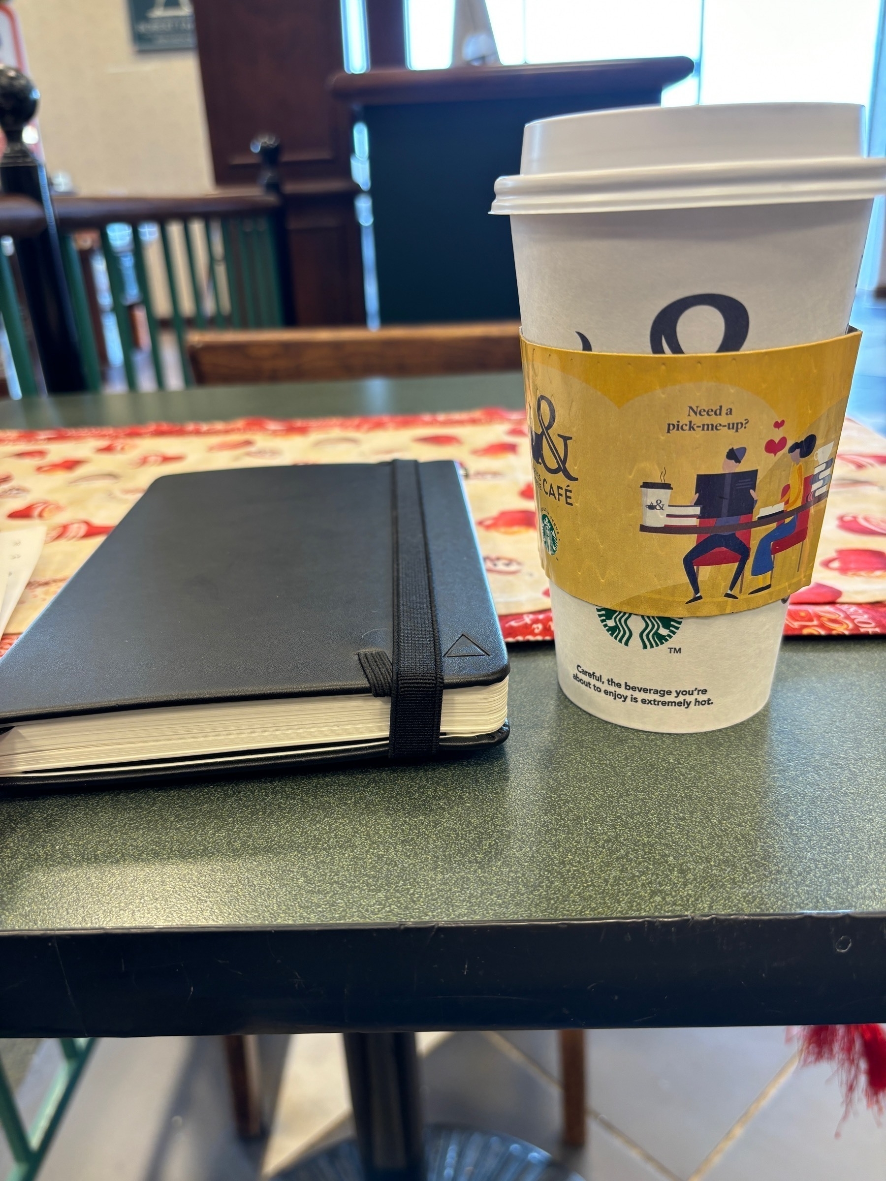 Journal and a Starbucks coffee cup on a table 