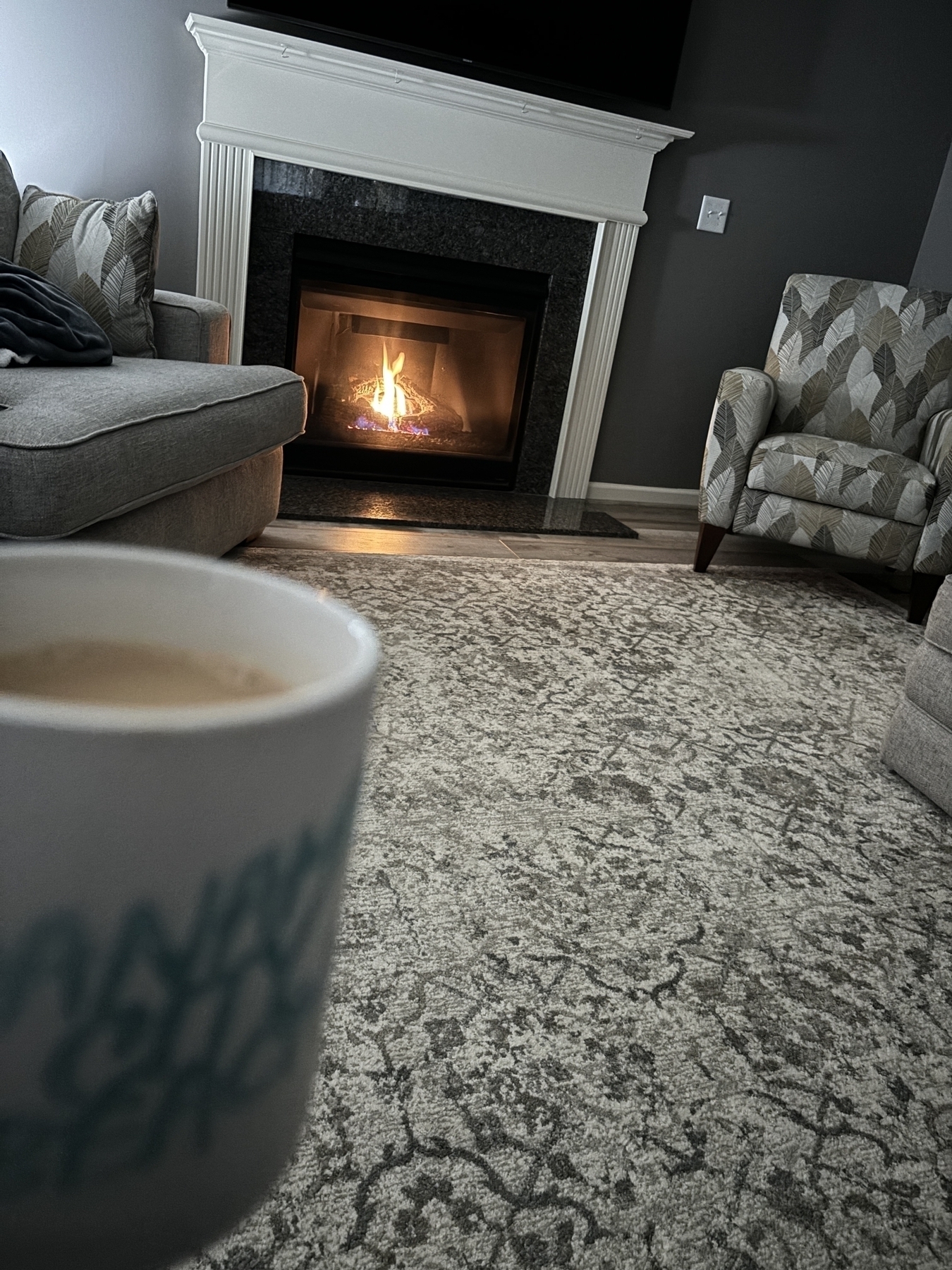 A mug of coffee in front of a fireplace 