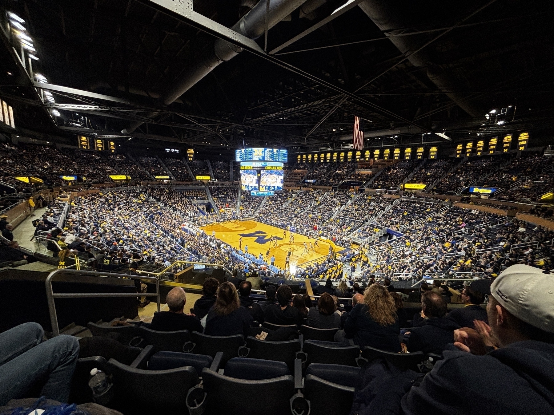 A large indoor arena is filled with spectators watching a basketball game.