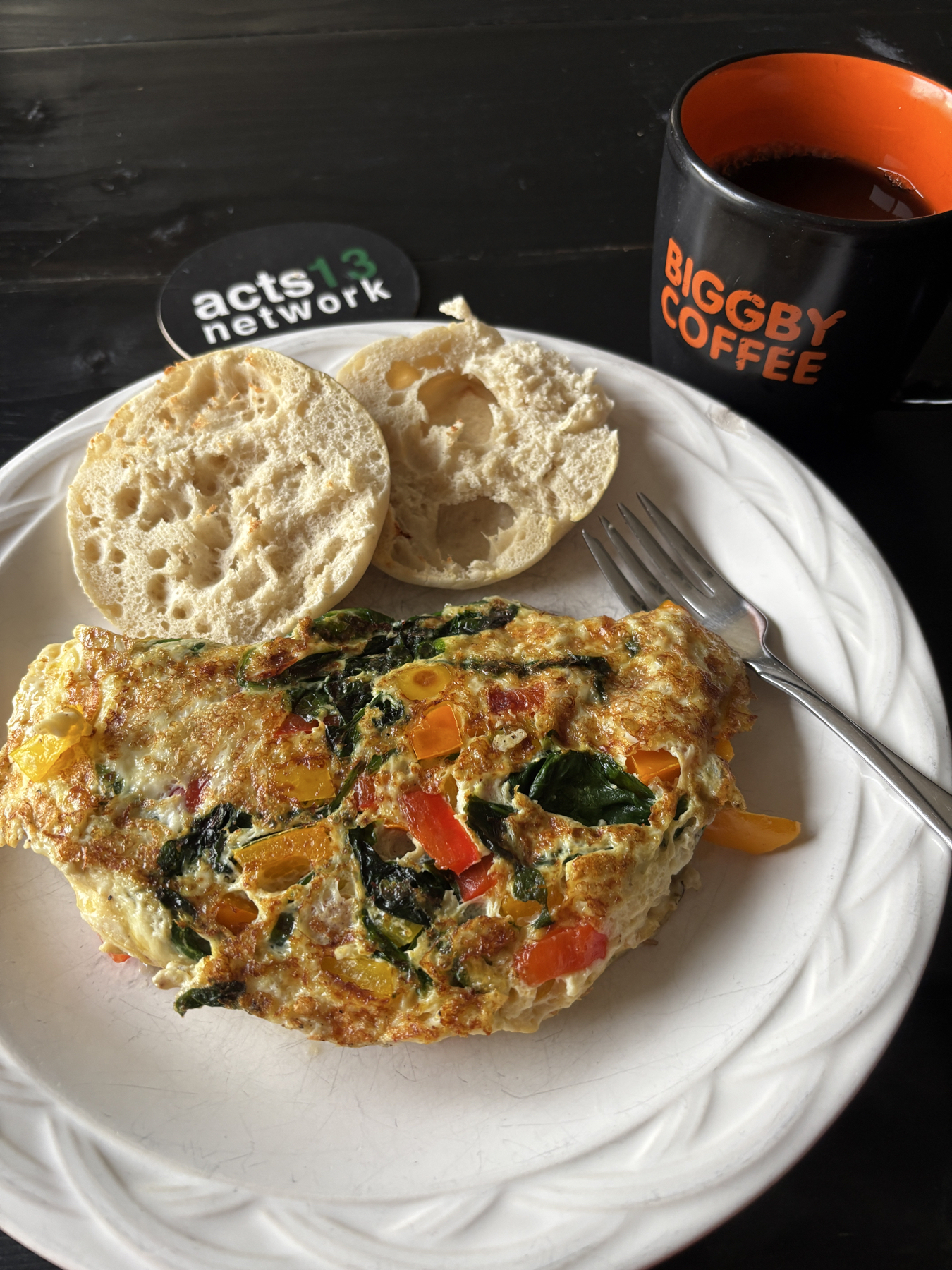 An egg white omelette with peppers and spinach accompanied with an English muffin and black coffee. 