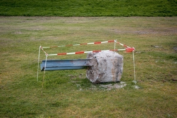 Ein ausgegrabener Pfosten am Strand, umrandet von vier Stäben und einem Absperrband.