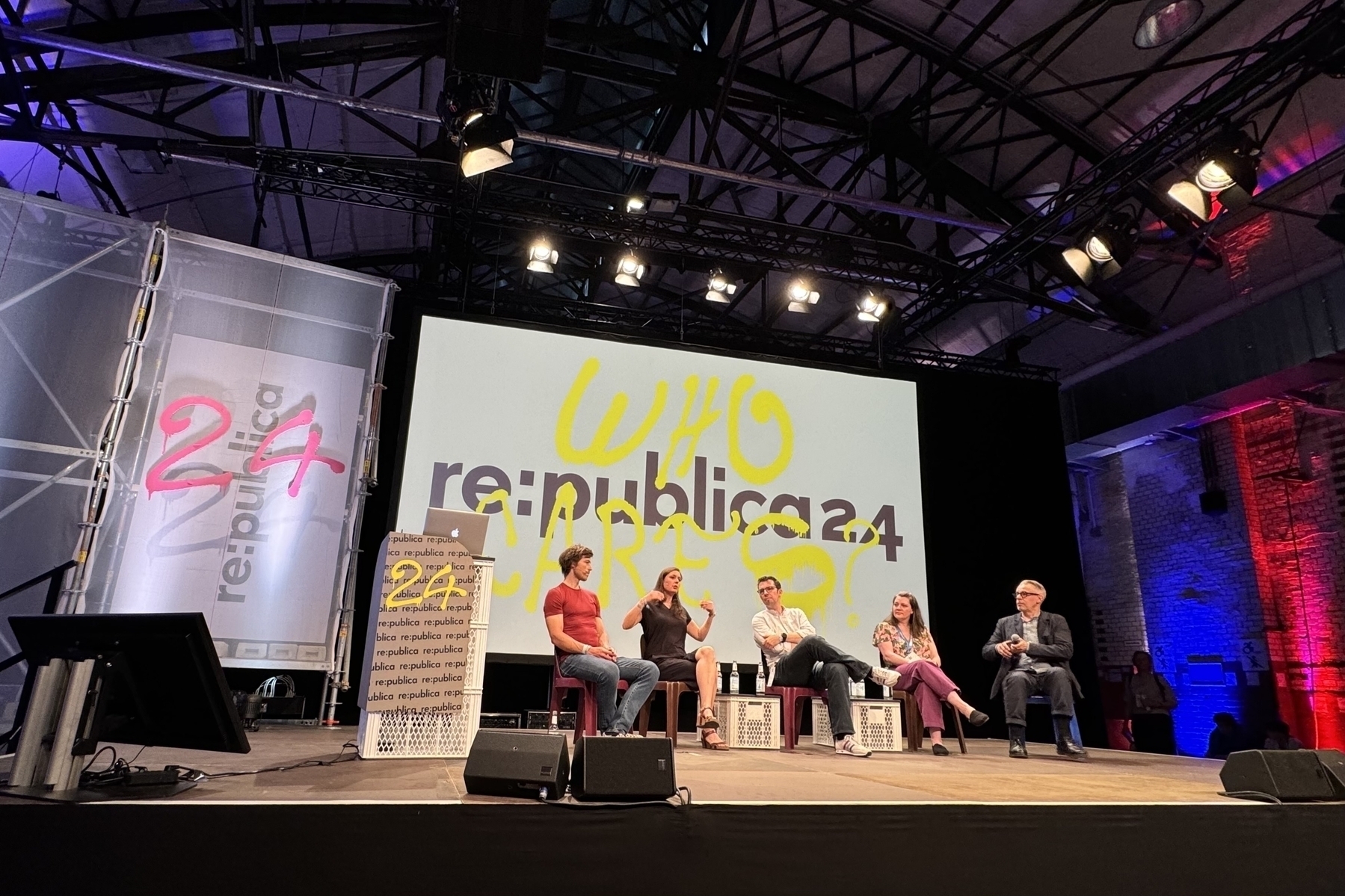 Eine Podiumsdiskussion auf der re:publica 24-Konferenz mit fünf Personen auf der Bühne, einem großen Bildschirm hinter "re:publica 24" und "WHO CARES?" und Bühnenbeleuchtung über dem Kopf.