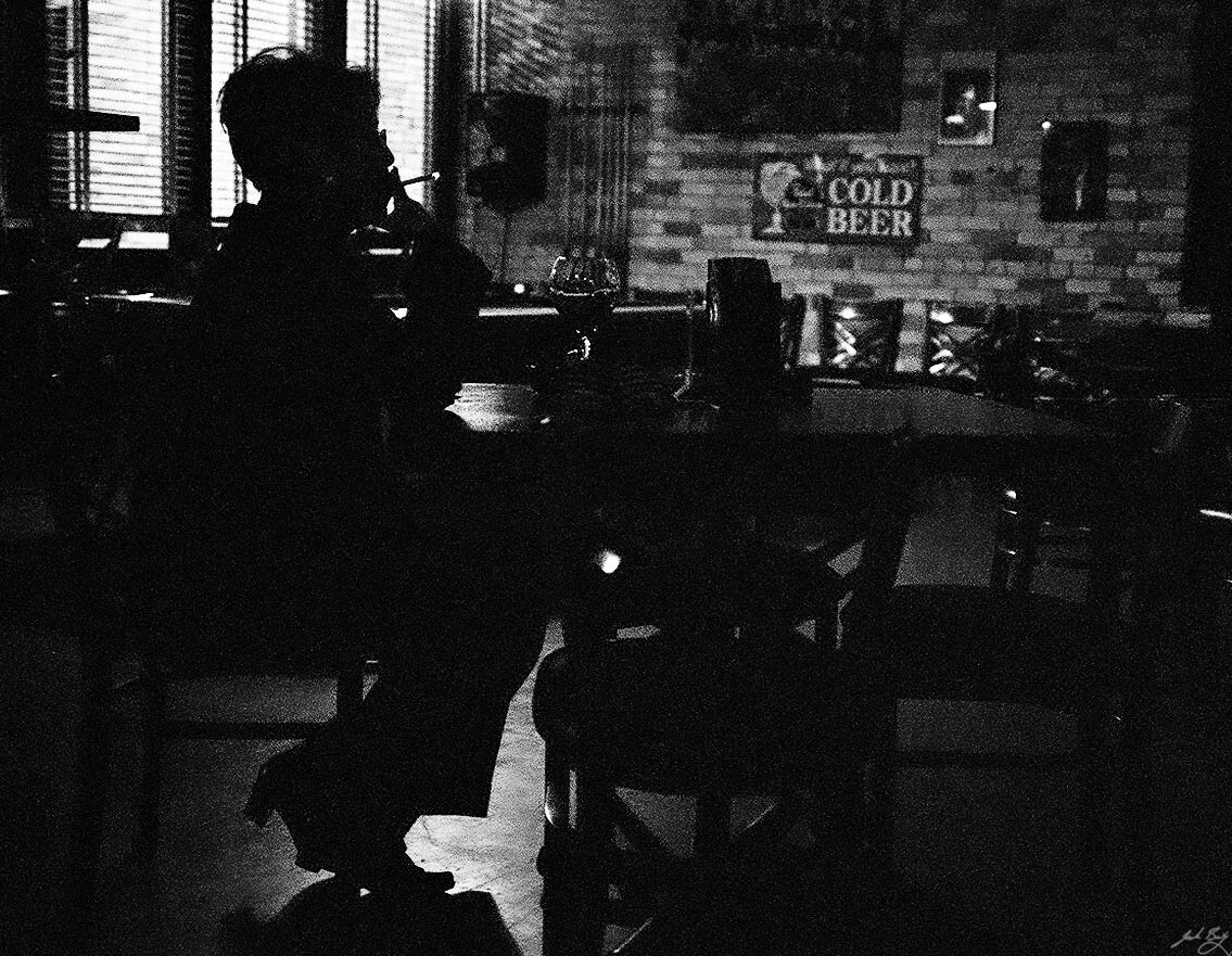 Black and white photo showing sillhouette of woman smoking in a restaurant