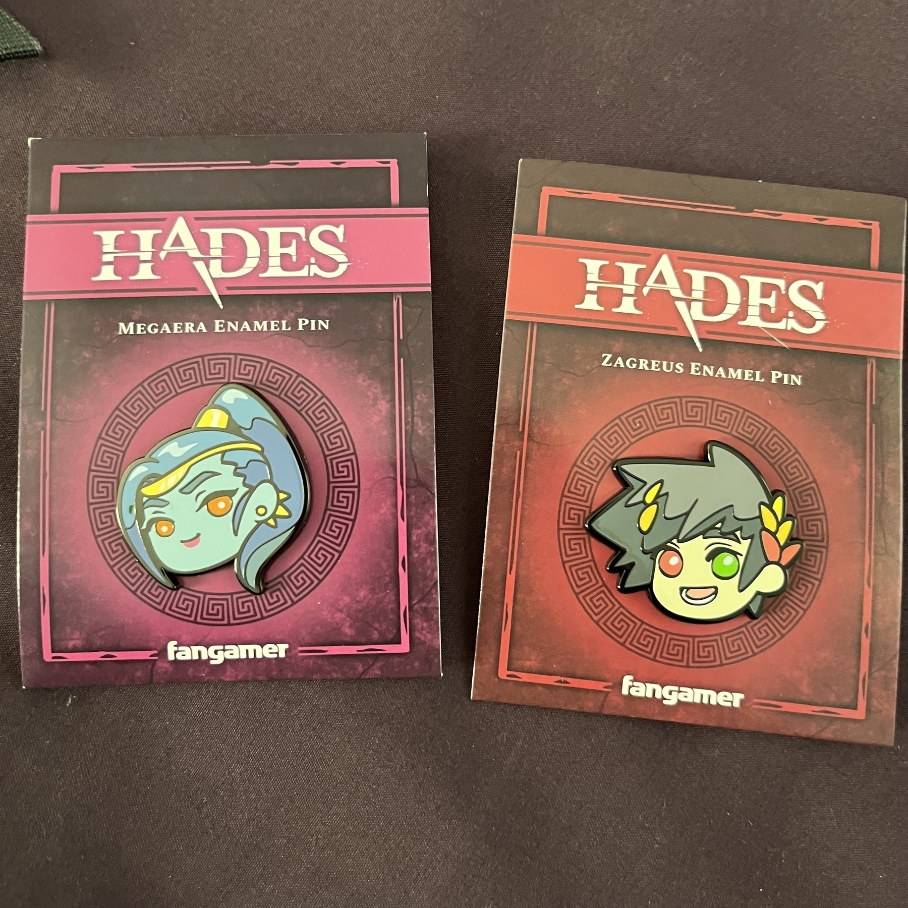 A pin of Megaera and a pin of Zagreus in their original packaging.