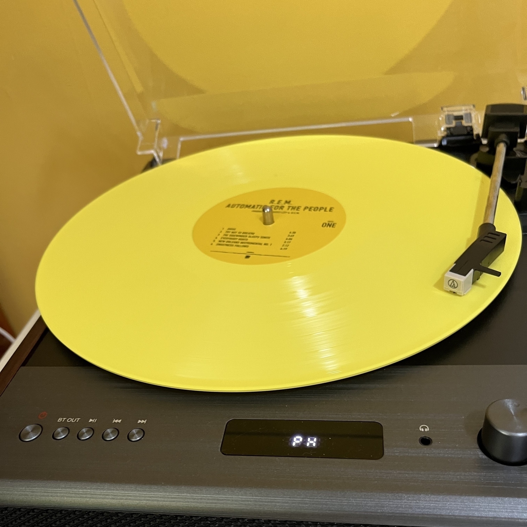 A yellow, vinyl LP of R.E.M.’s Automatic for the People plays on a turntable.