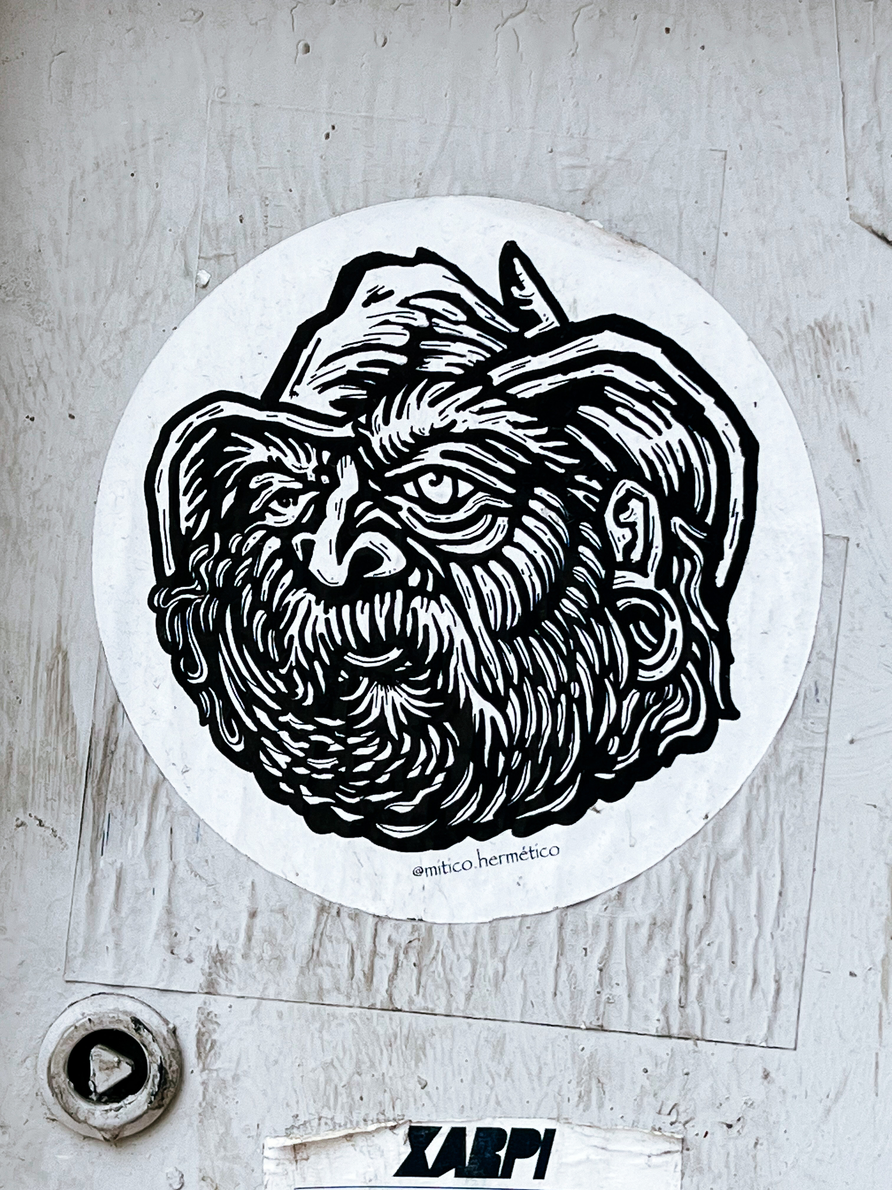 Black and white sticker, drawing of a bearded man in a hat. 