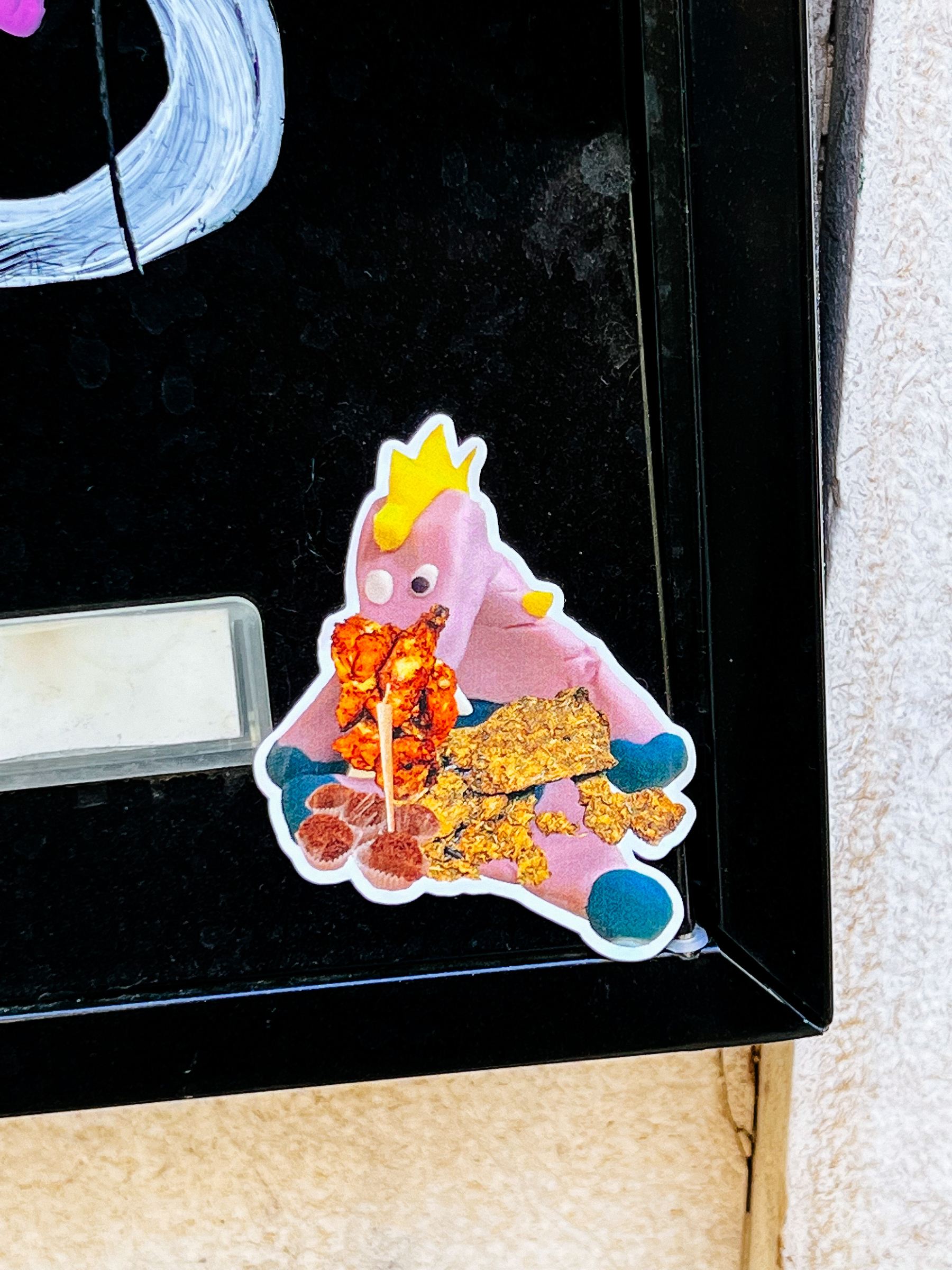 Sticker of what looks like a pink plastic unicorn gorging on candy. 
