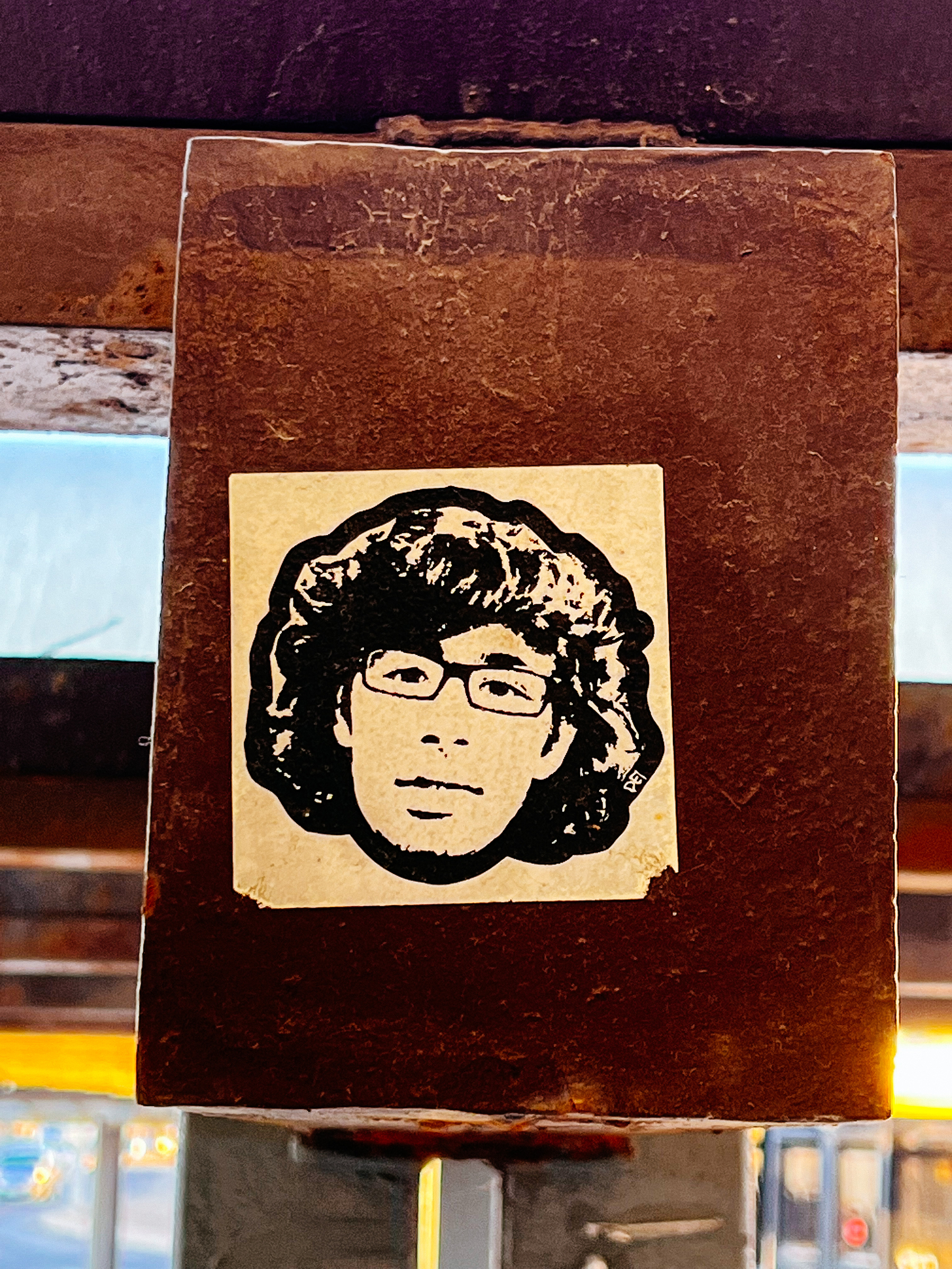 Sticker of a drawing of a man’s face. He has glasses and bushy hair. 