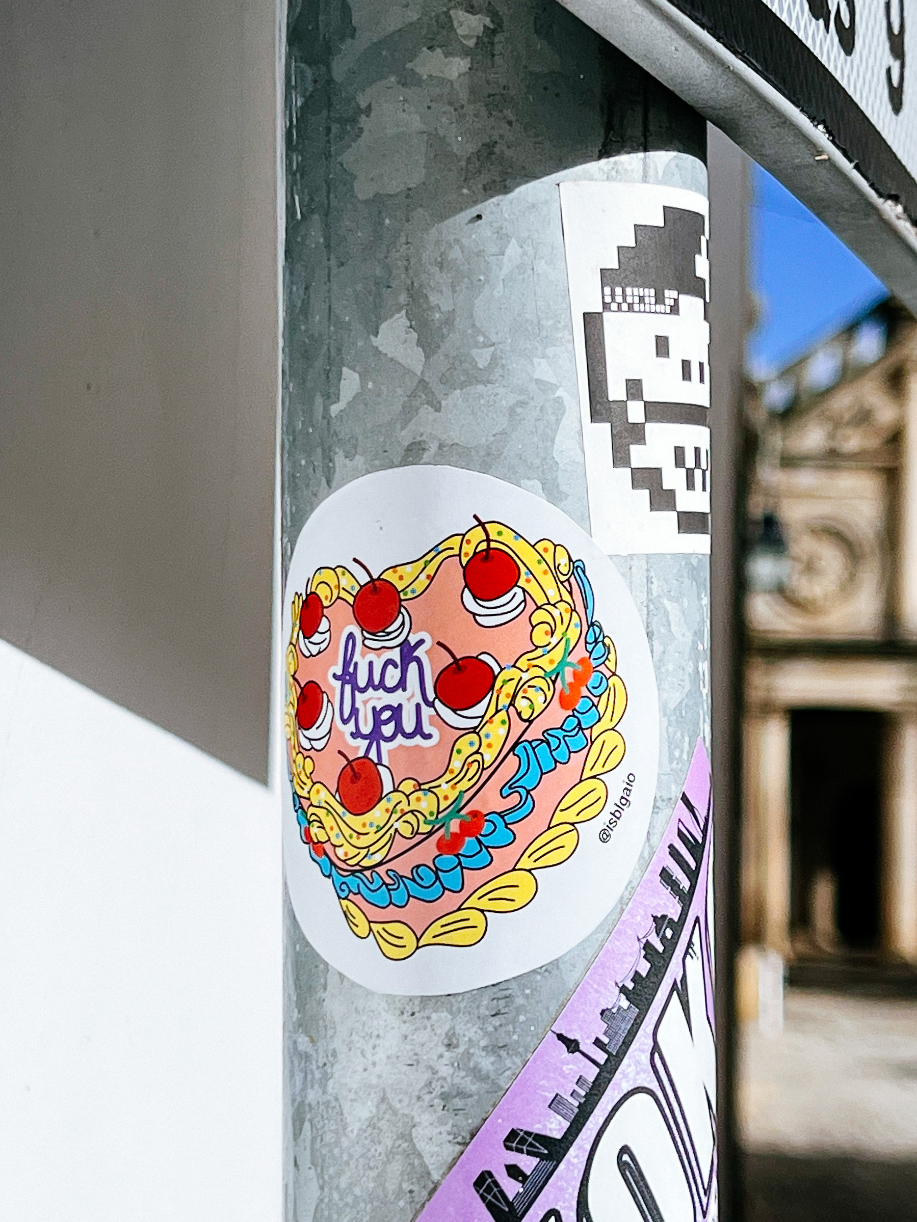 Sticker with the drawing of a heart shaped cake, with the expression “F%^* You” written on it. 