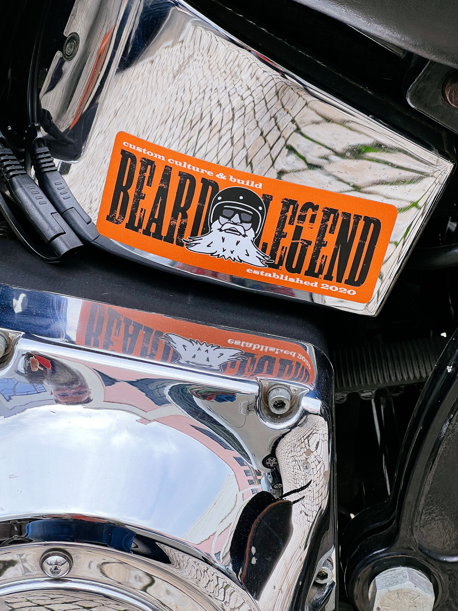 Sticker on a motorcycle engine, “Beard Legend” written on it, with a bearded man in a helmet