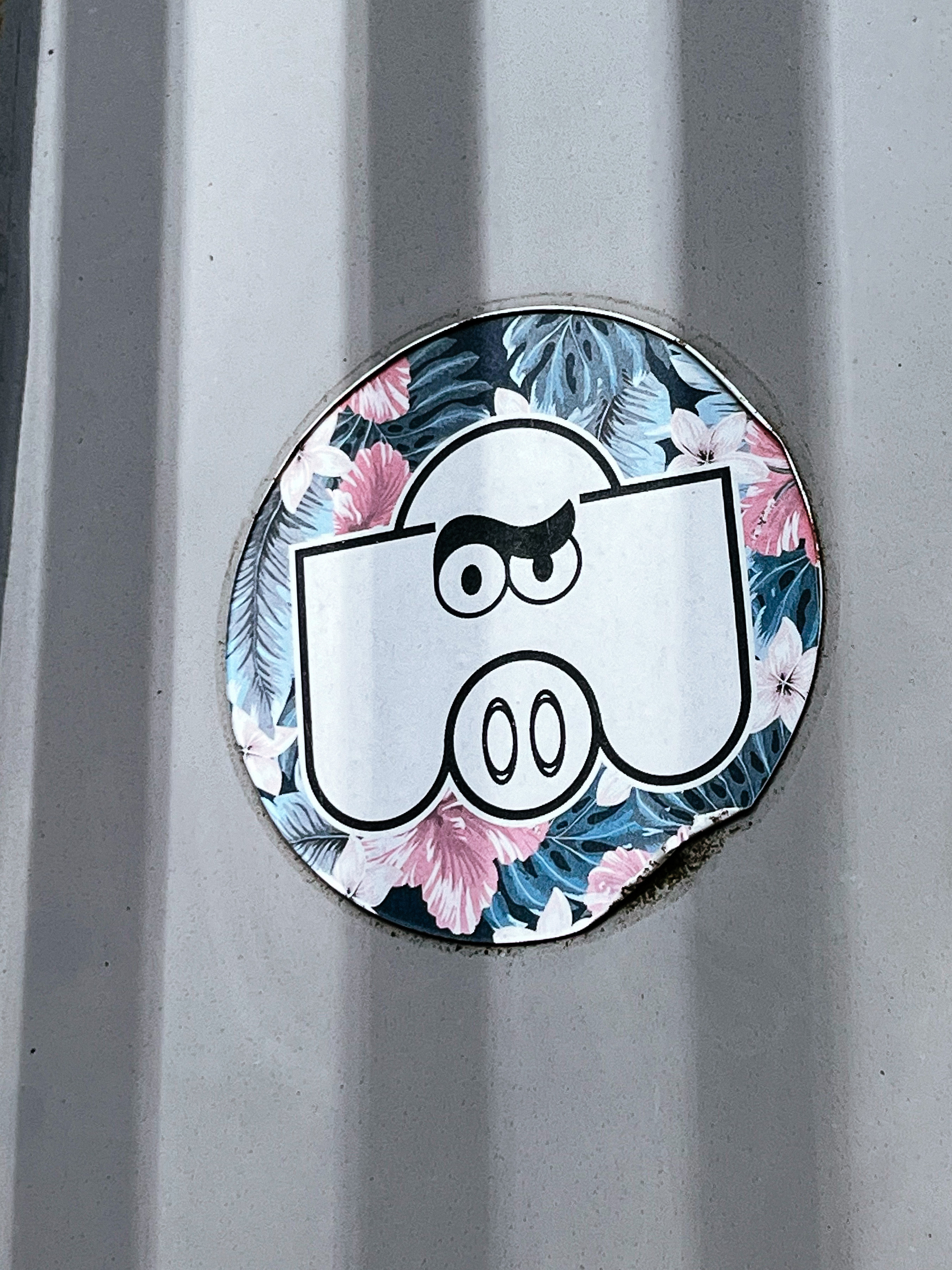 Sticker with the cartoon face of a frowning pig. 