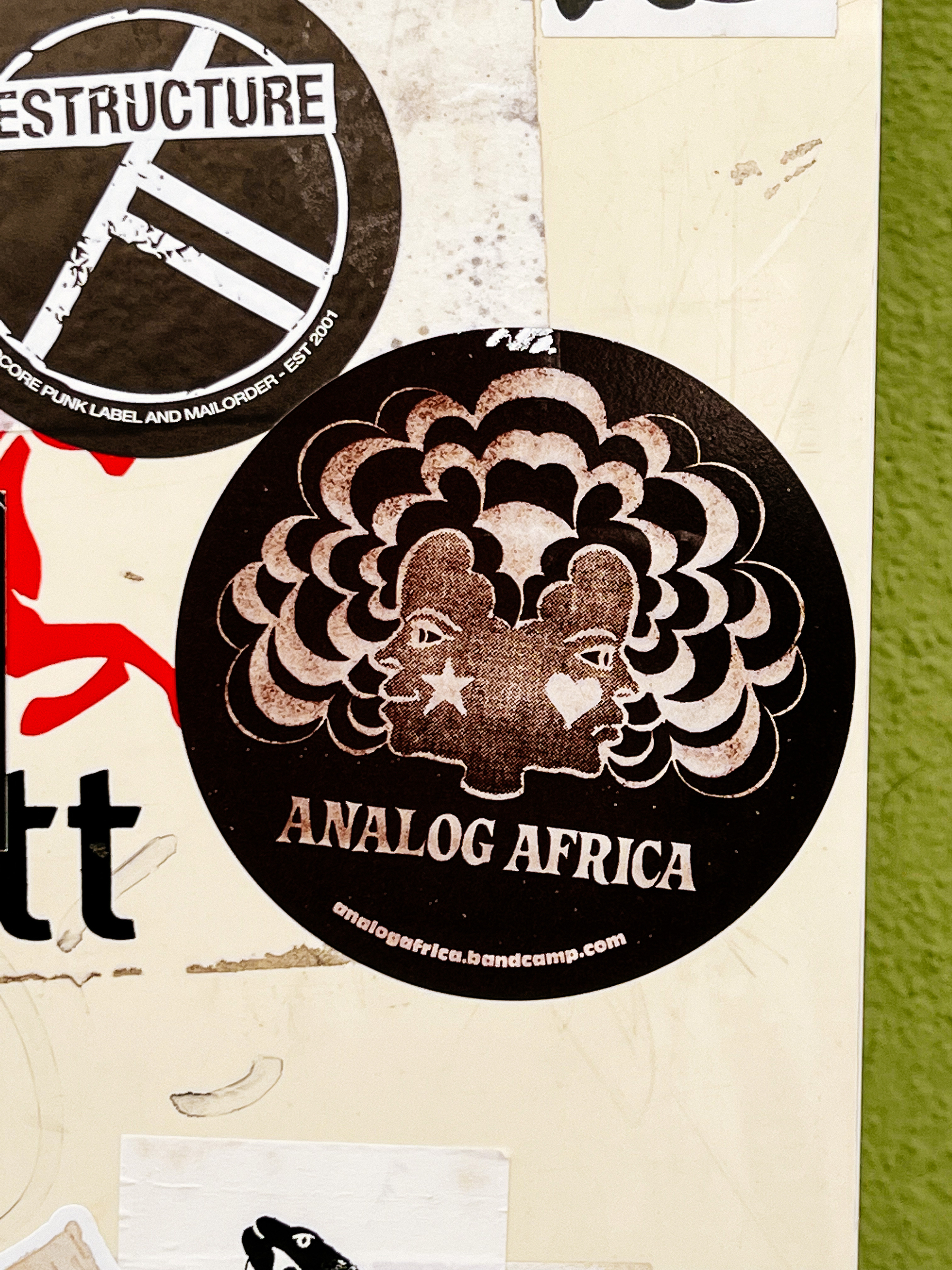 Sticker for “Analog Africa”, with a two faced women design. On one cheek there’s a star, on the other a heart. 