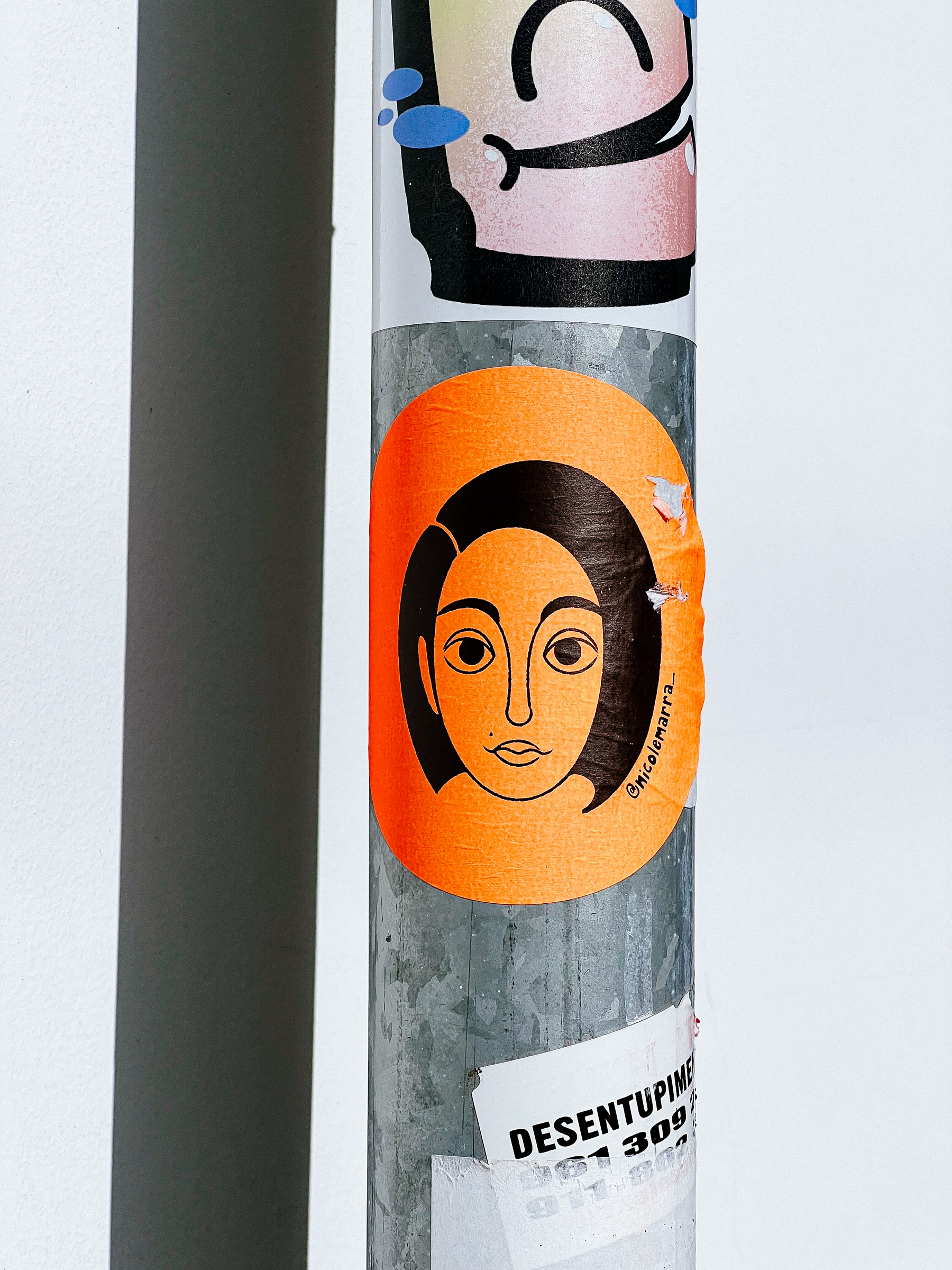 Orange sticker with a drawing of a woman’s face. 