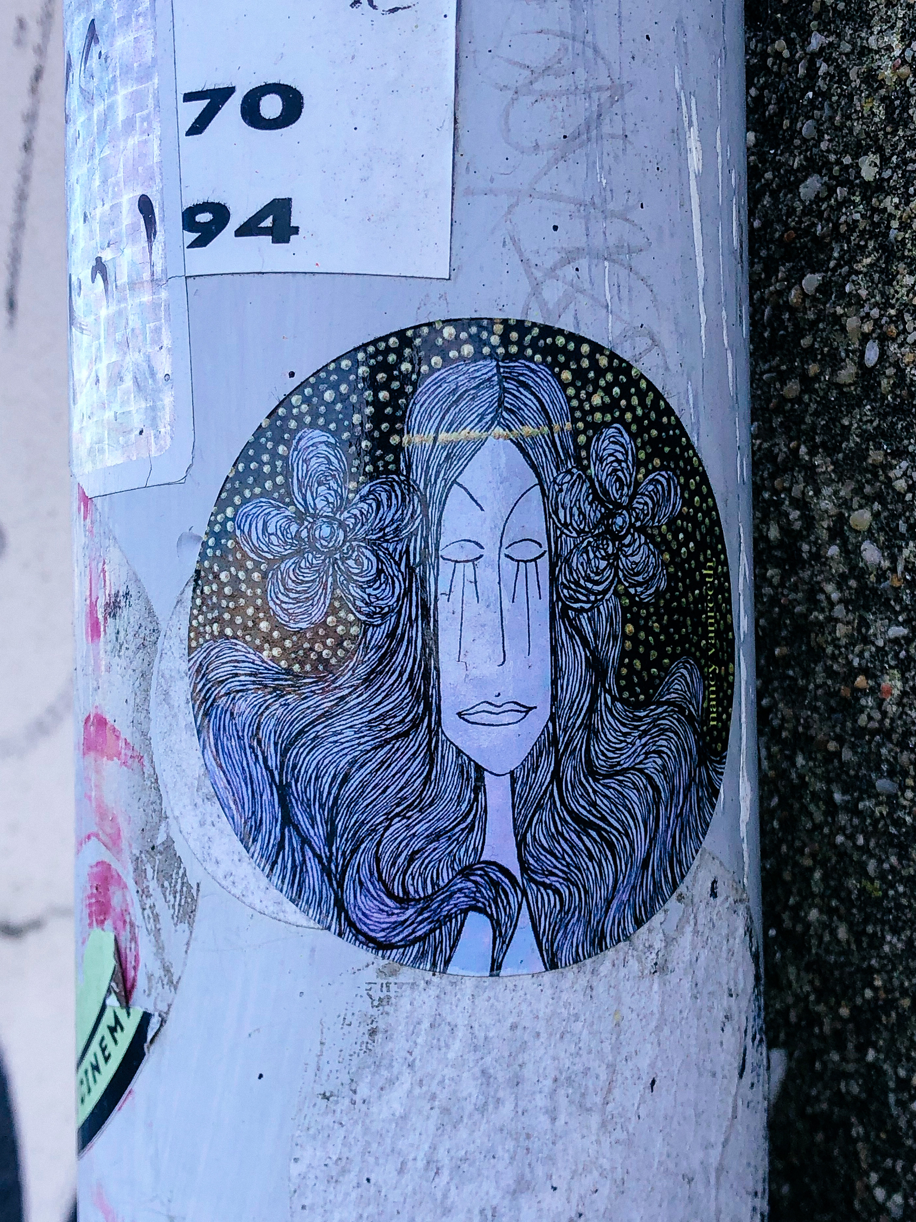 Sticker, a woman with long black hair, and tears rolling down her face. Part of the hair is tied up into two flowers. 
