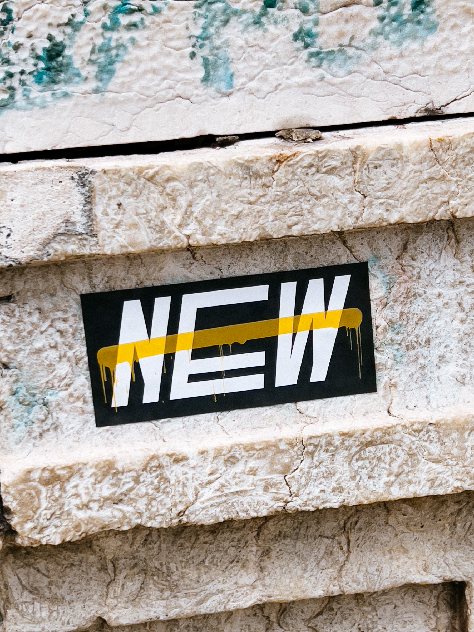 A sticker with the word “NEW”, and a dash of yellow over it. 