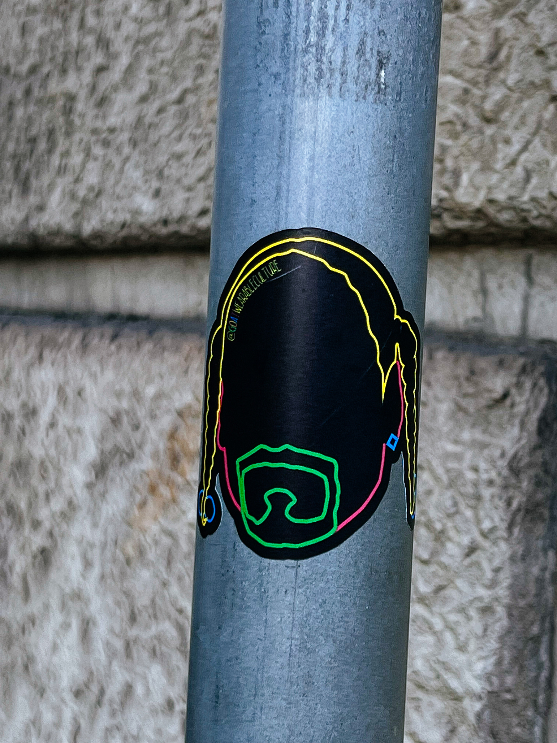 Sticker with the contour of a man’s face, using only a thin line. Goes from pink, to yellow, with a green goatee.