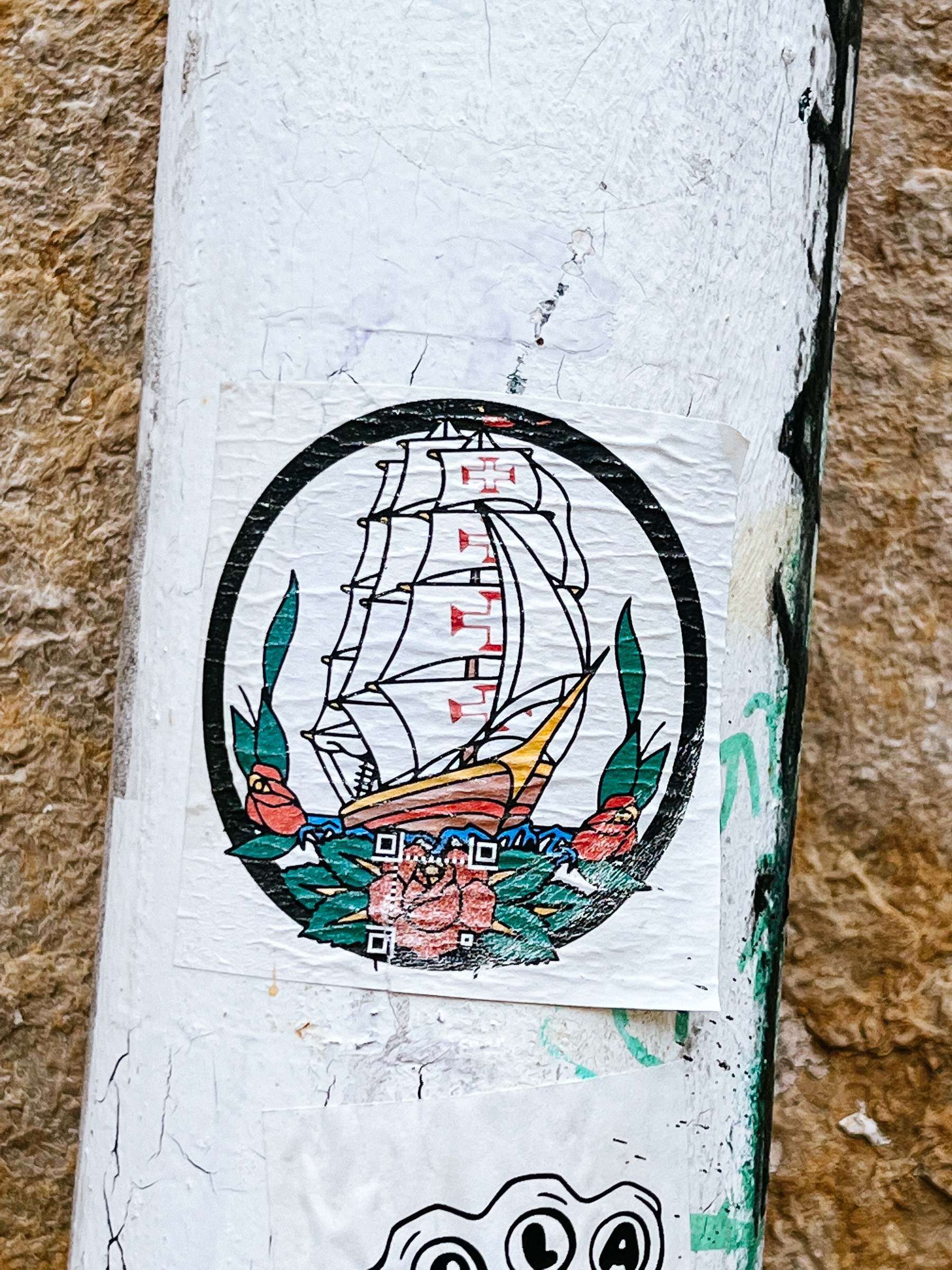 Sticker of a classic sailor tattoo, with a ship and flowers, but the classic ship on these tattoos has been replaced by a Portuguese caravel.