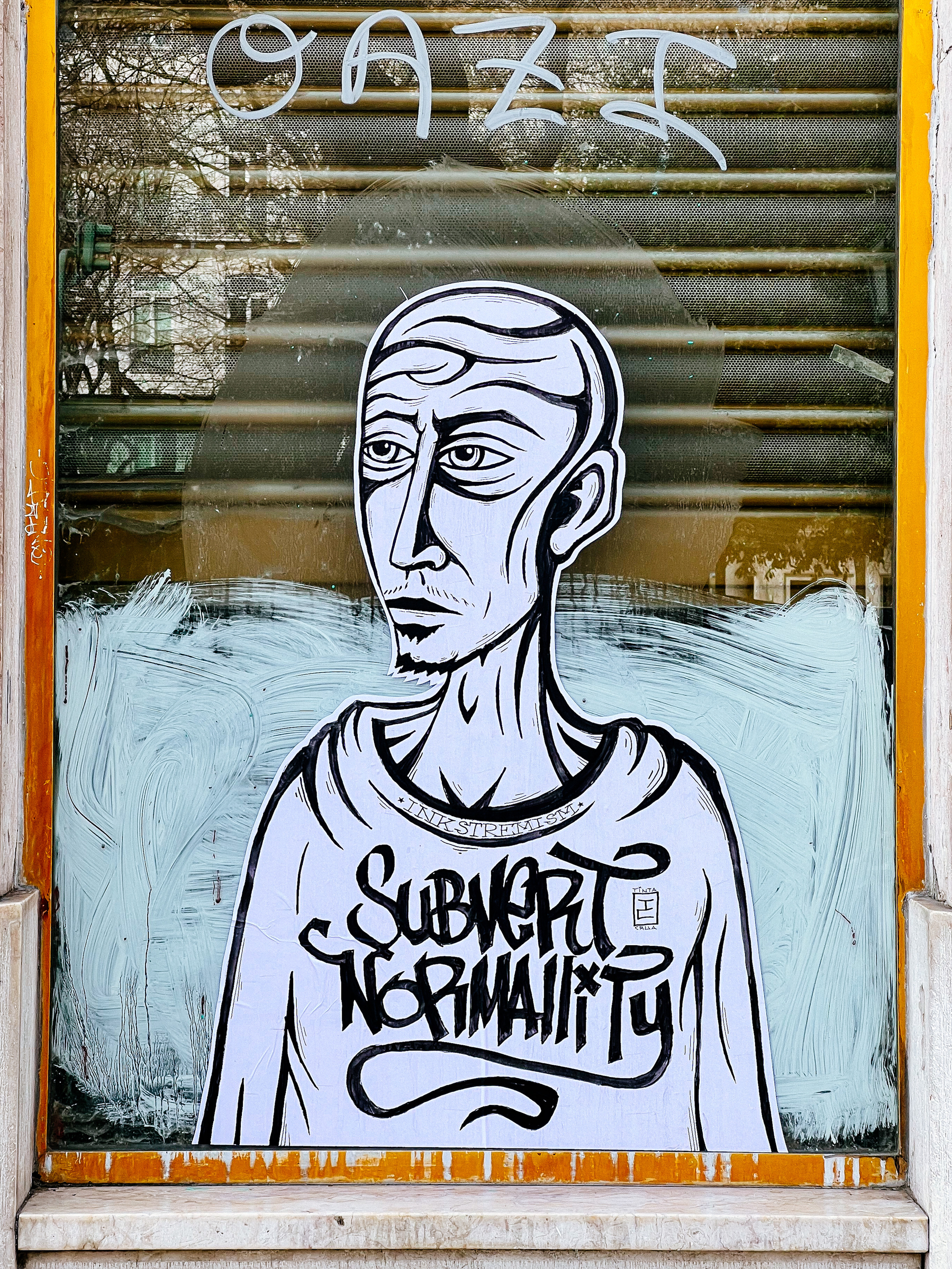 Big sticker on a window, with the words “Subvert normality”. 