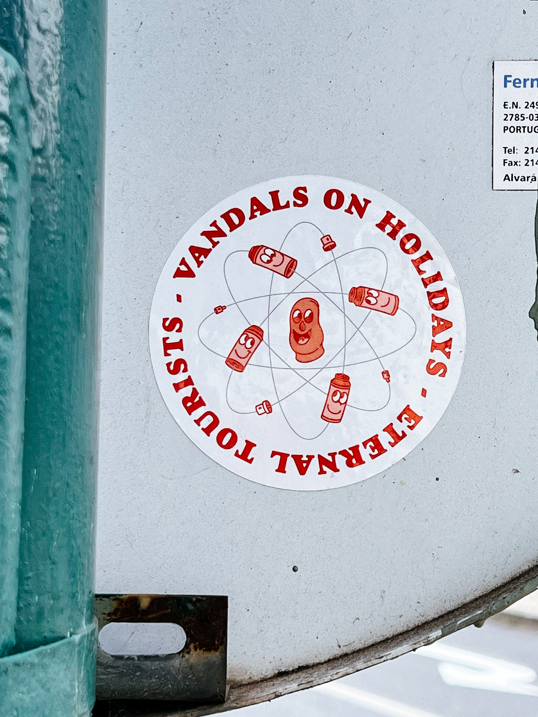 “Vandals on holidays - eternal tourists”, written around an image that looks like an atom, but with spray paint cans. 