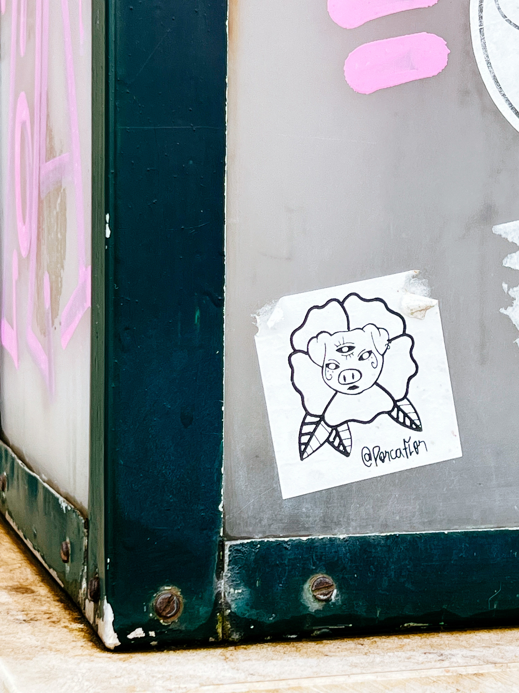 Sticker of a tattoo design, with a pig’s face surrounded by a flower. The pig has a third eye. 