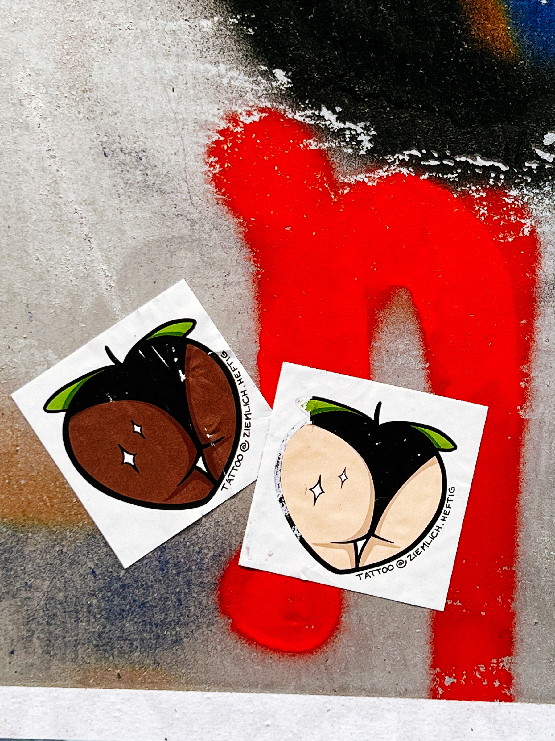 Stickers of what can look like fruit, or maybe a “behind”. One dark skinned, one light skinned. 