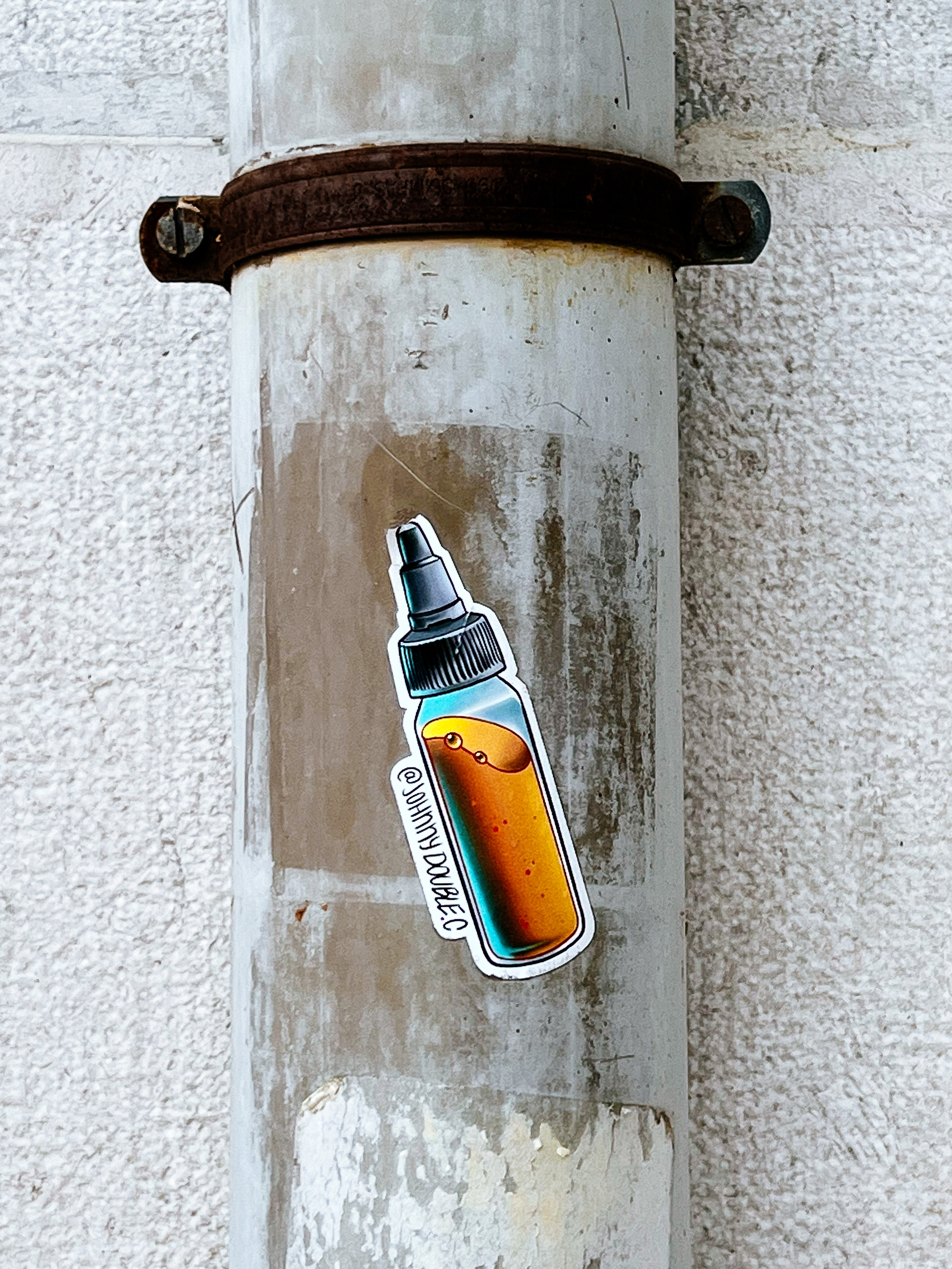 Sticker with the drawing of a tattoo ink bottle, with orange ink. 