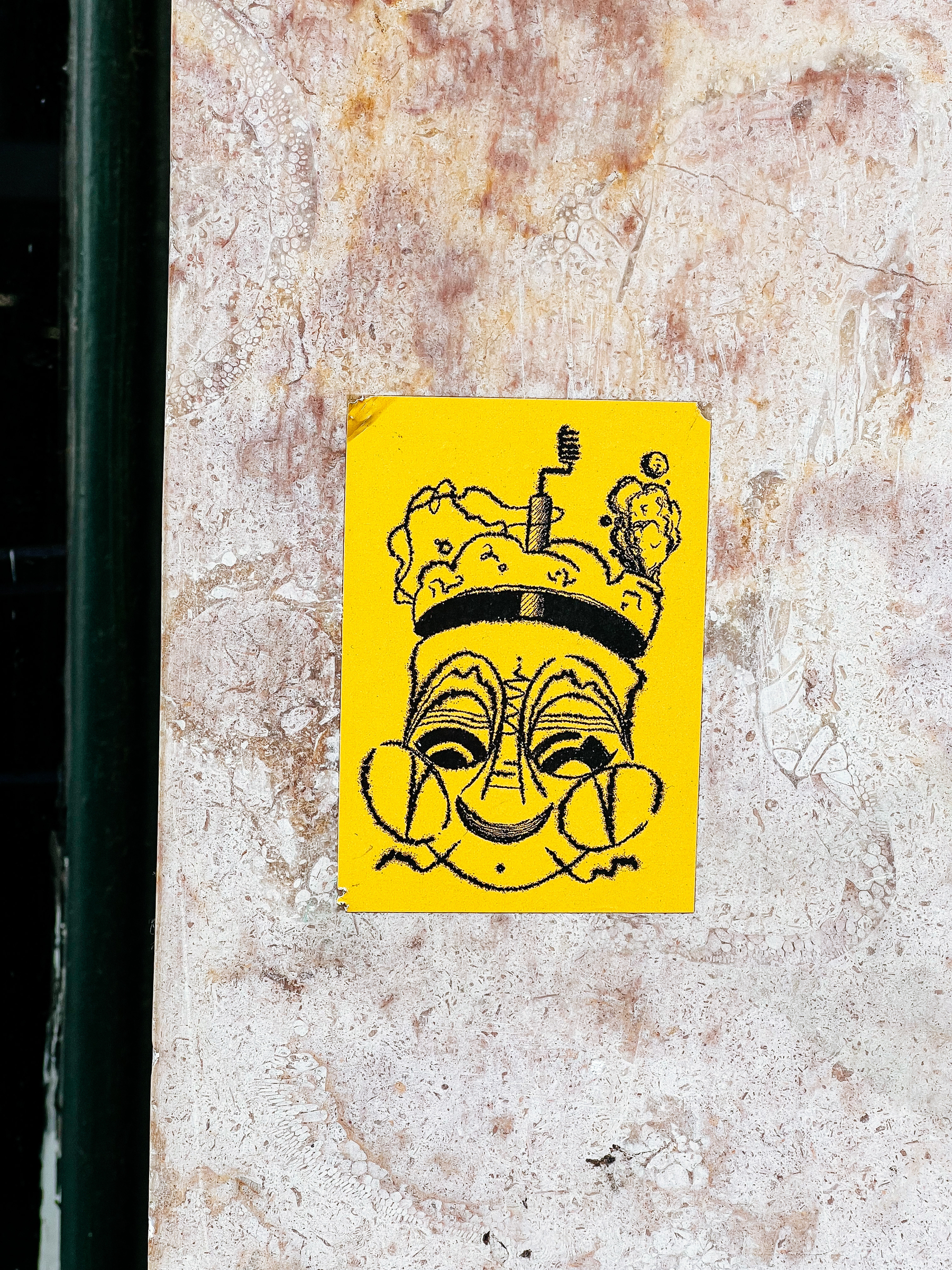 Sticker of a face, on a yellow background. The face is drawn with heavily pixelated lines. 