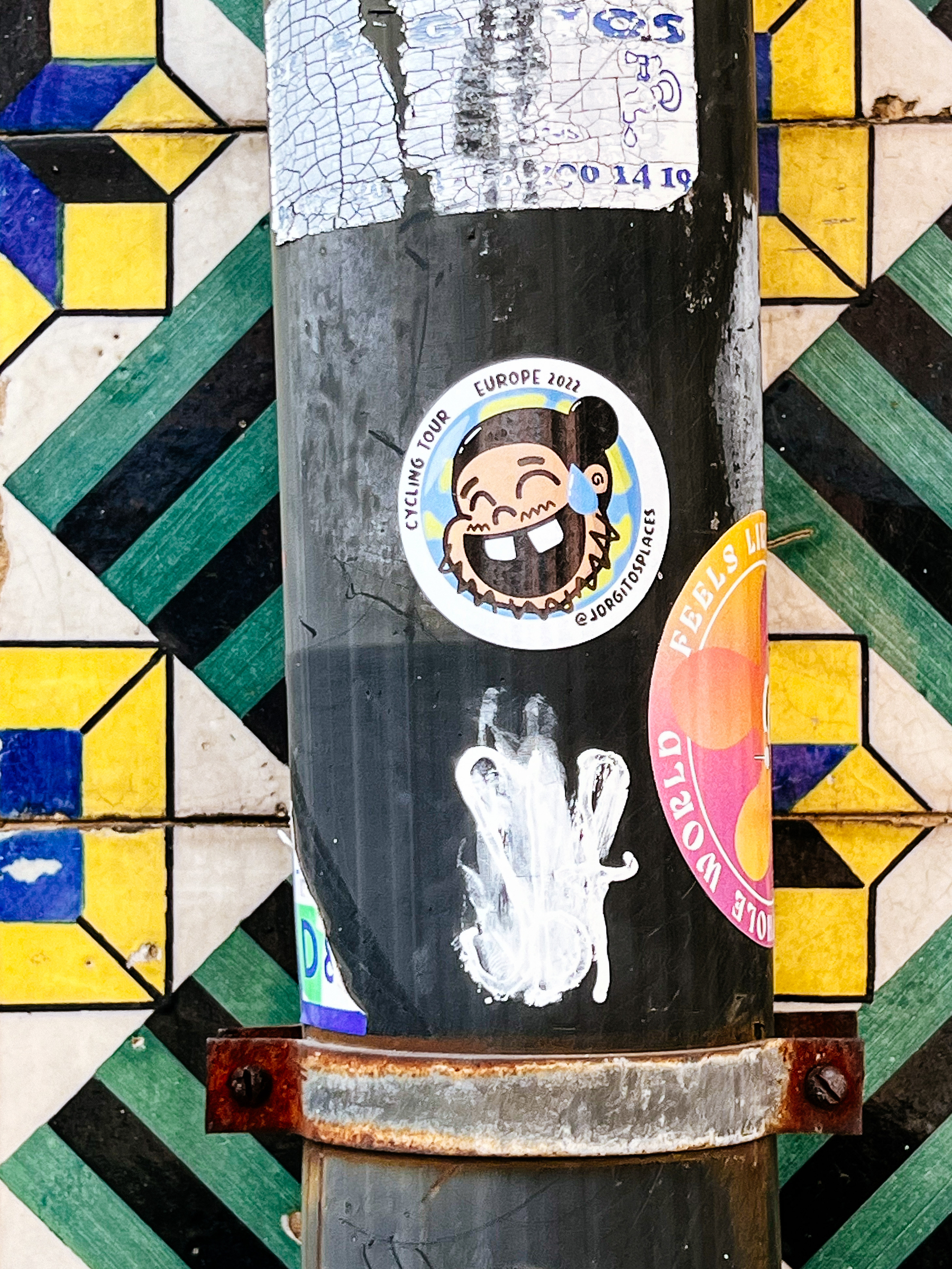 Sticker with a smiling face, cartoony. Tiled wall. 