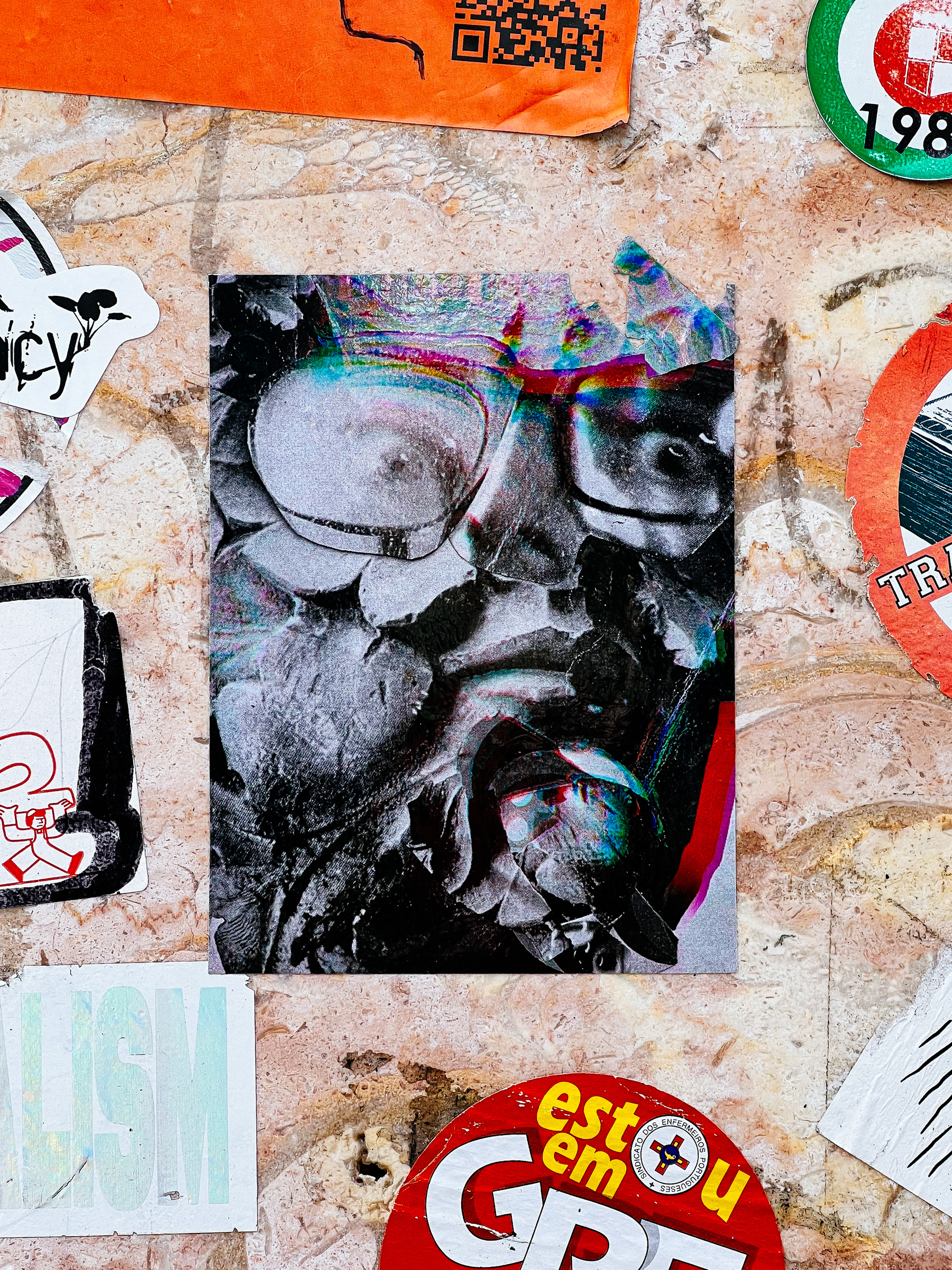 Sticker with a photo of a man with glasses, with a filter applied, making him look strange and deformed. 