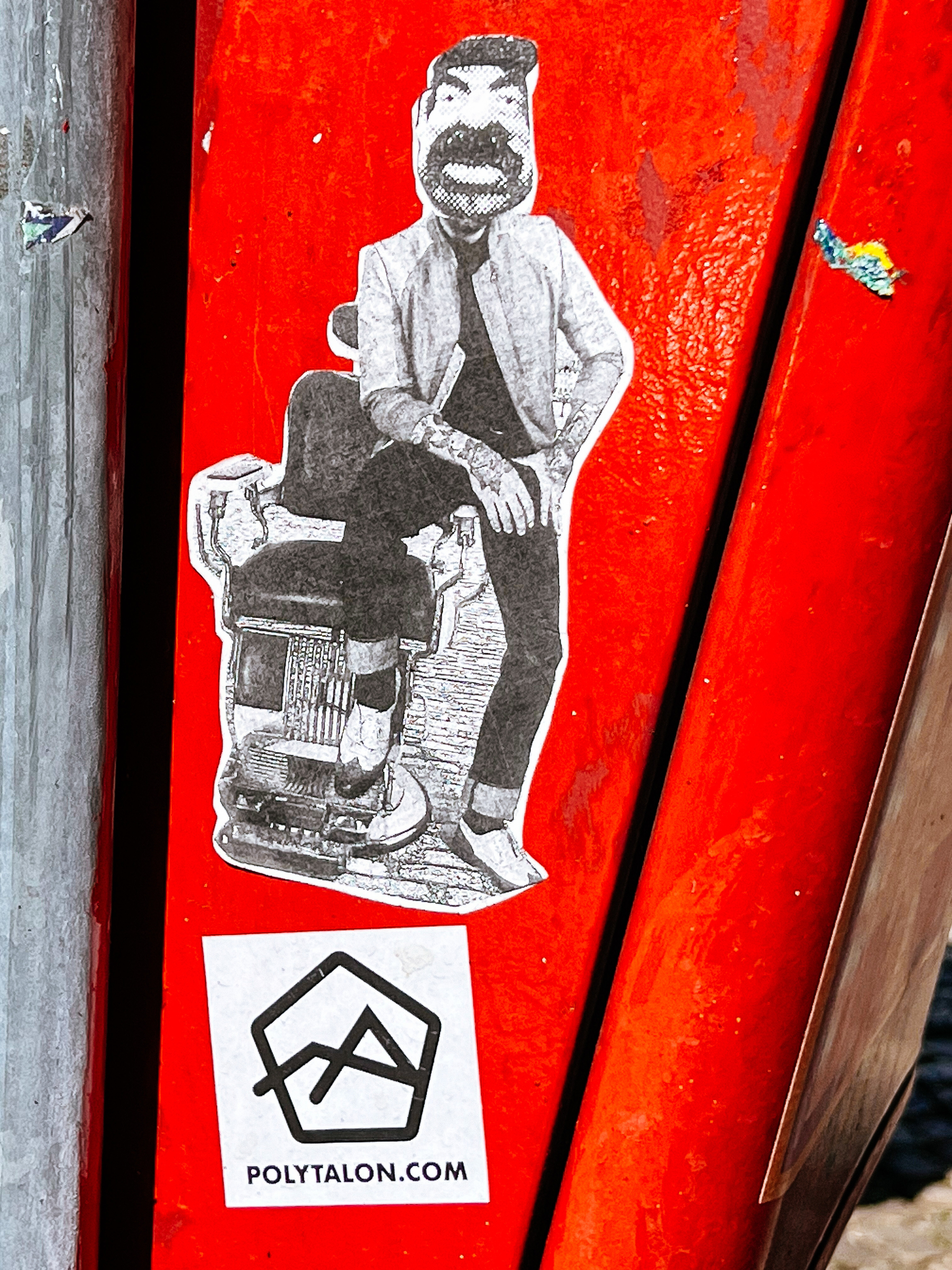 Sticker with the photo of an hipster barber, sitting on the arm of his barber chair. His face has been swapped, he now has a Saddam face. 