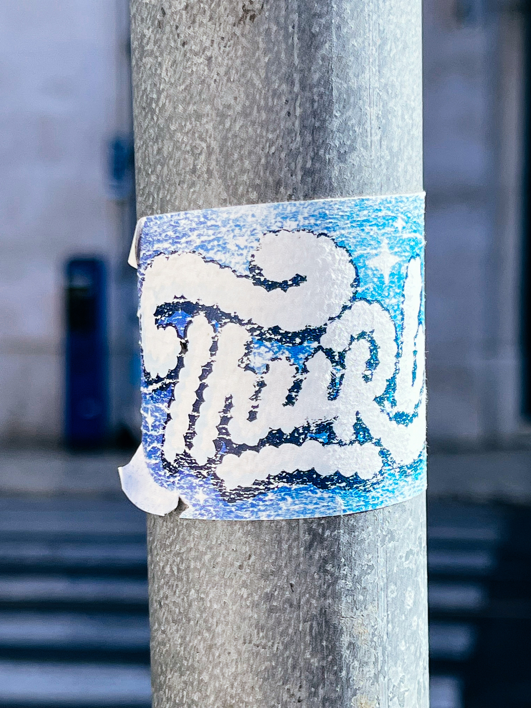 Sticker with a part of a word, “Thurb”, written in a font that looks like it’s made of clouds. 