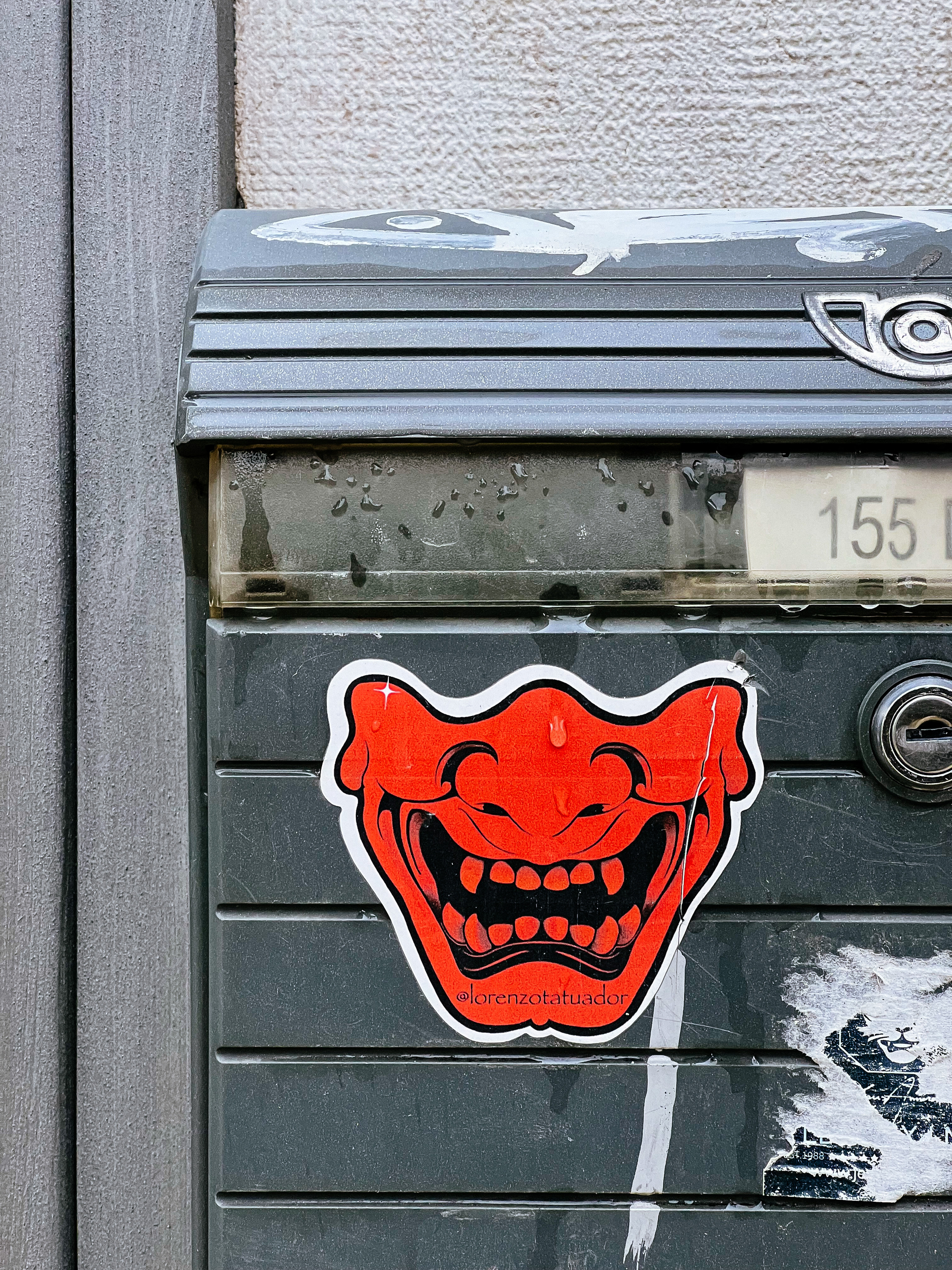 Sticker with a drawing of the bottom half of a face, mouth open wide, in red. 