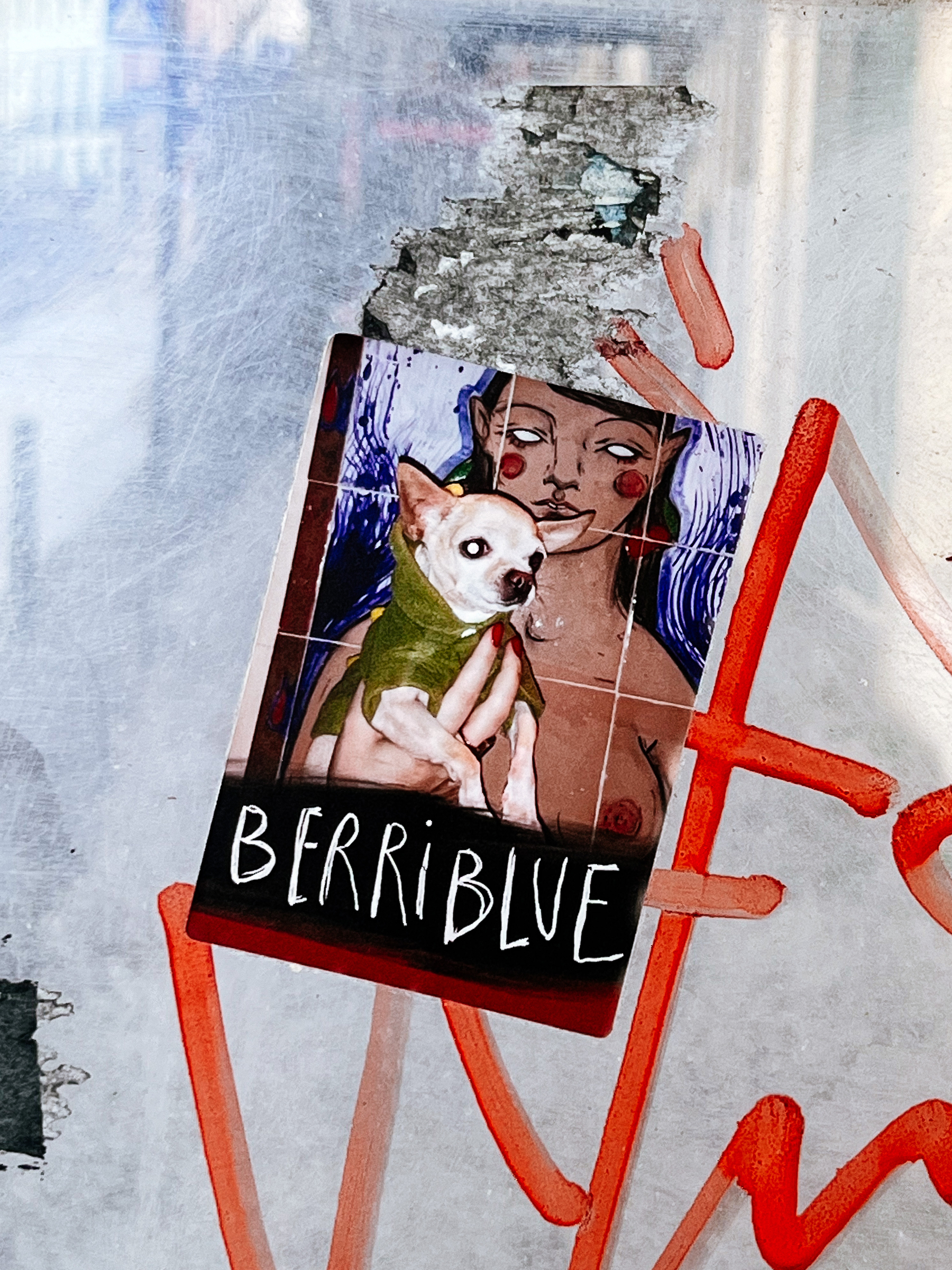Sticker with “Berriblue” written on the bottom, and a composite. There’s a photo of a chihuahua, being held by a woman. The woman is a drawing though, expect the hand holding the dog. That’s real.