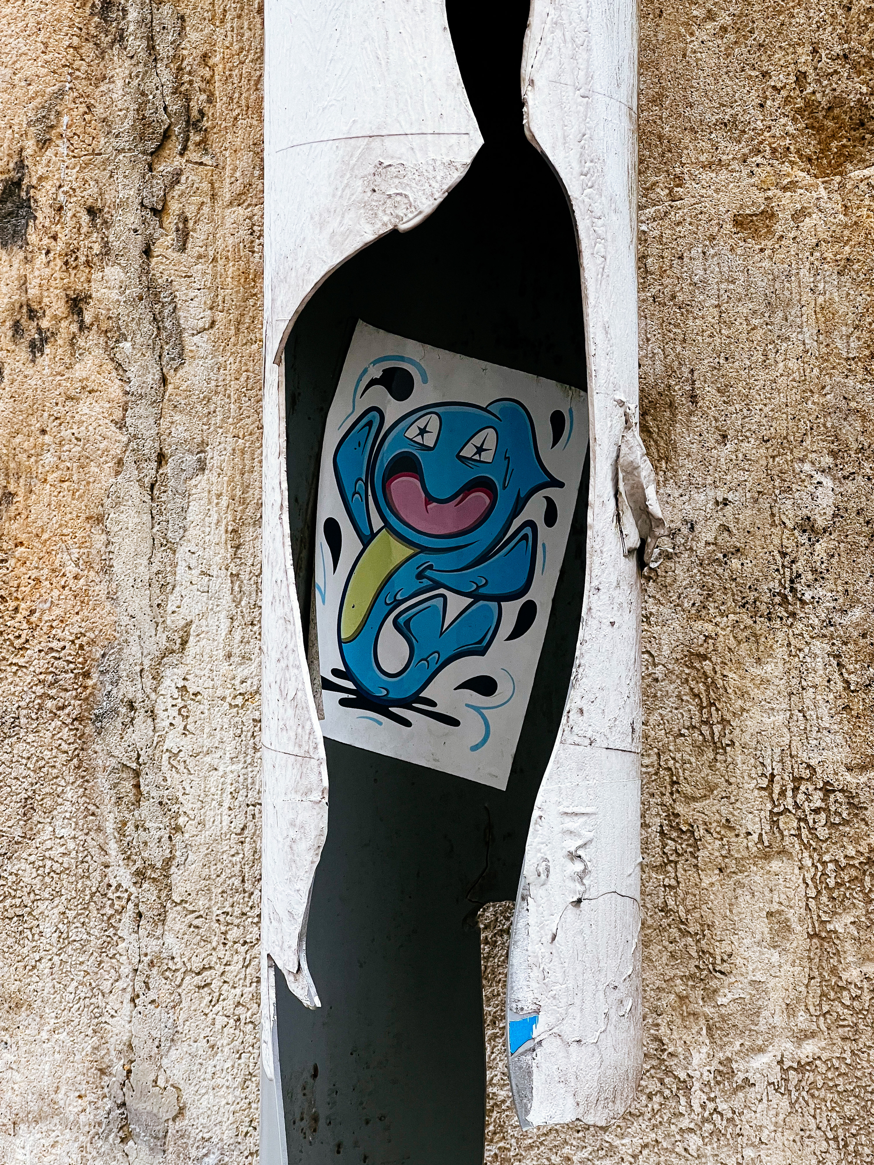 A cartoon shark in a sticker, stuck inside a broken pipe. 