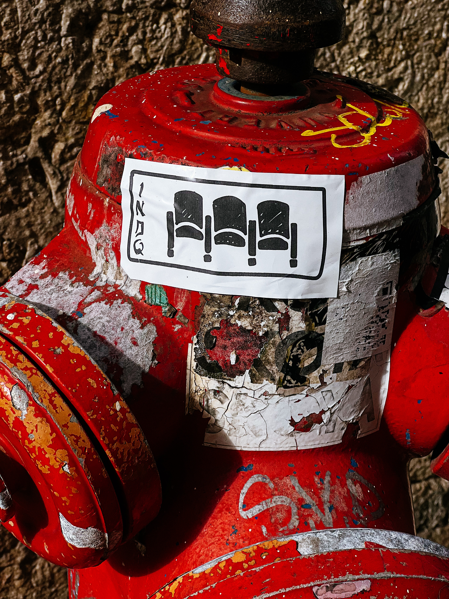 Sticker with a drawing of three theater chairs, glued to a fire hydrant. 