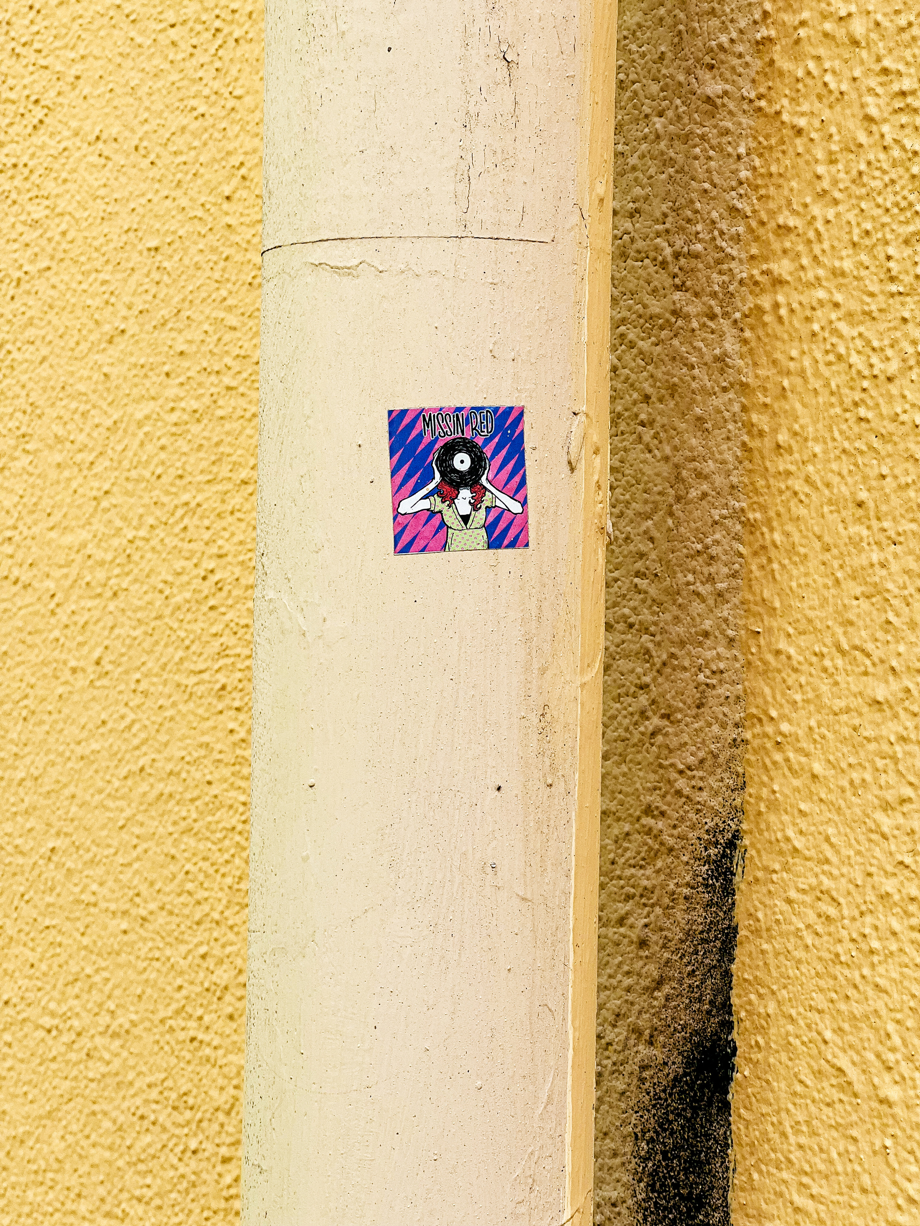 Sticker with a drawing of a red haired woman holding a vinyl LP covering her face, and the words “missin red”. 