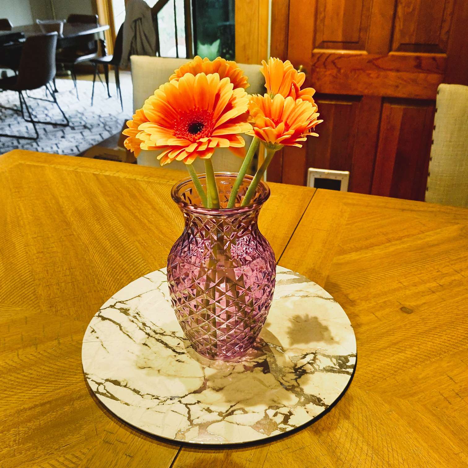 Purple vase with orange flowers on a wooden table