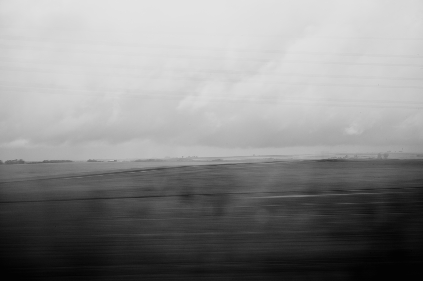 Blurry, rainy landscape through a train window in black and white