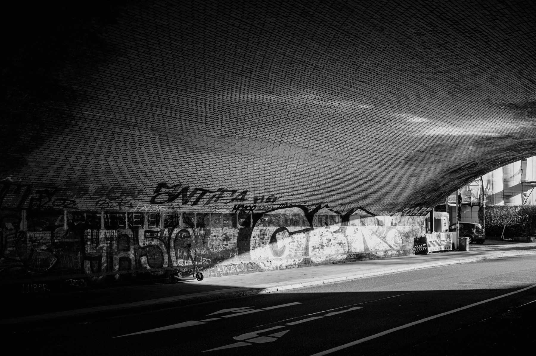 Under the bridge, with some graffities on the wall,  lack and white