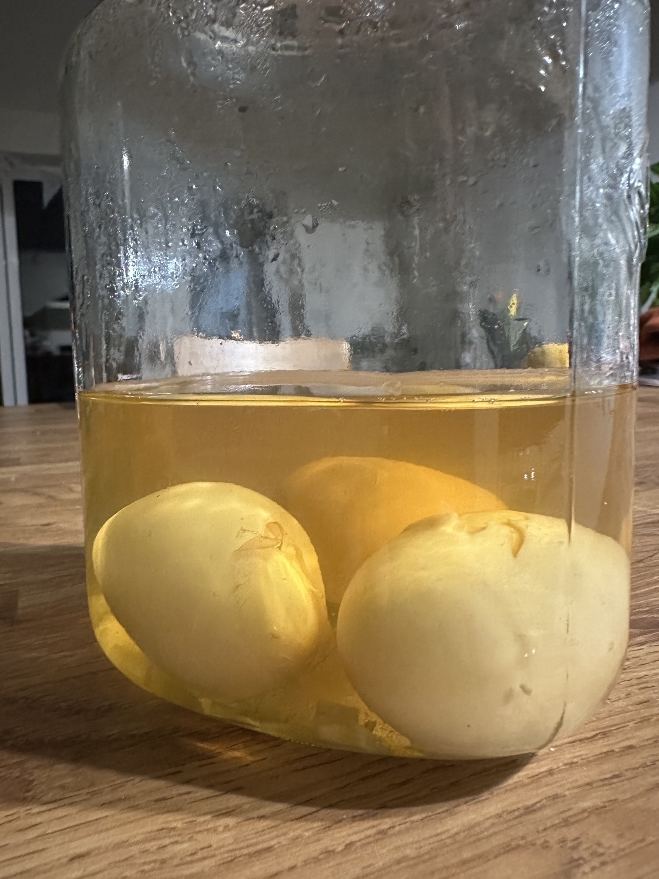 Three pickled eggs in a jar, sitting on a table.