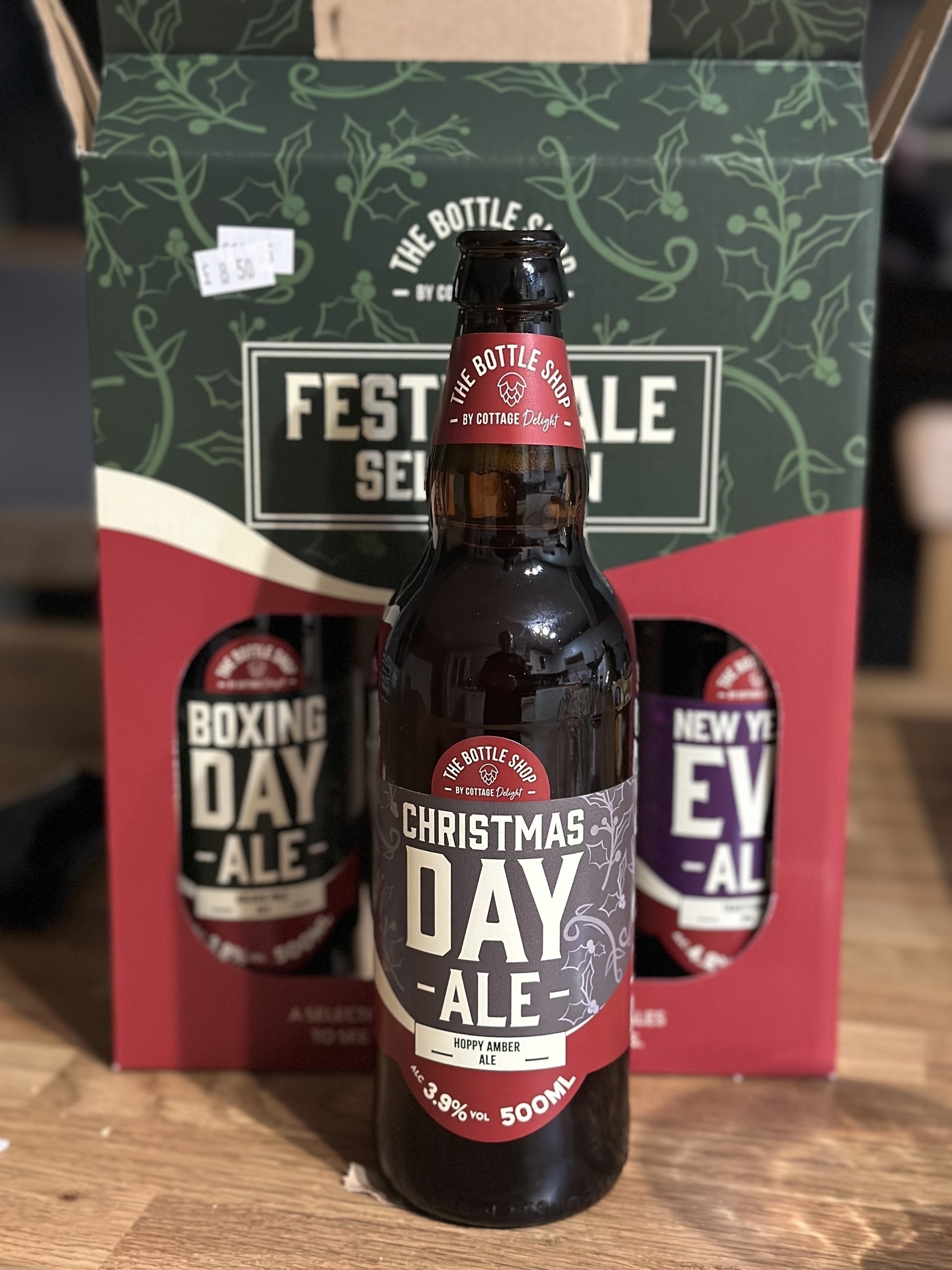 A bottle of Christmas Day Ale is positioned in front of a festive ale gift box containing two other bottles labeled Boxing Day Ale and New Year's Eve Ale.