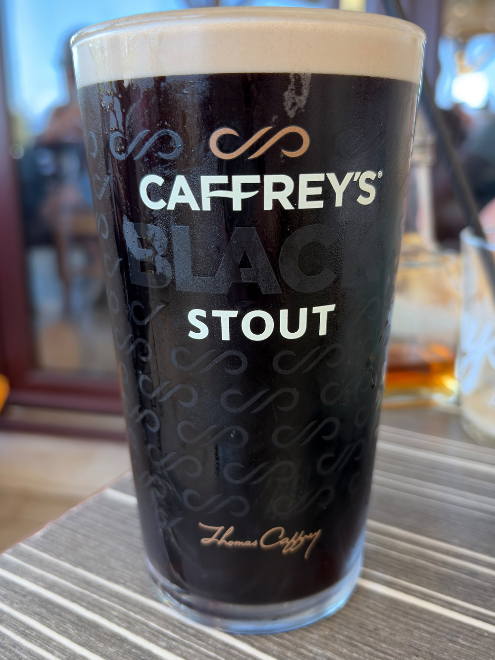 A pint glass filled with dark beer labeled Caffrey's Black Stout sits on a table.