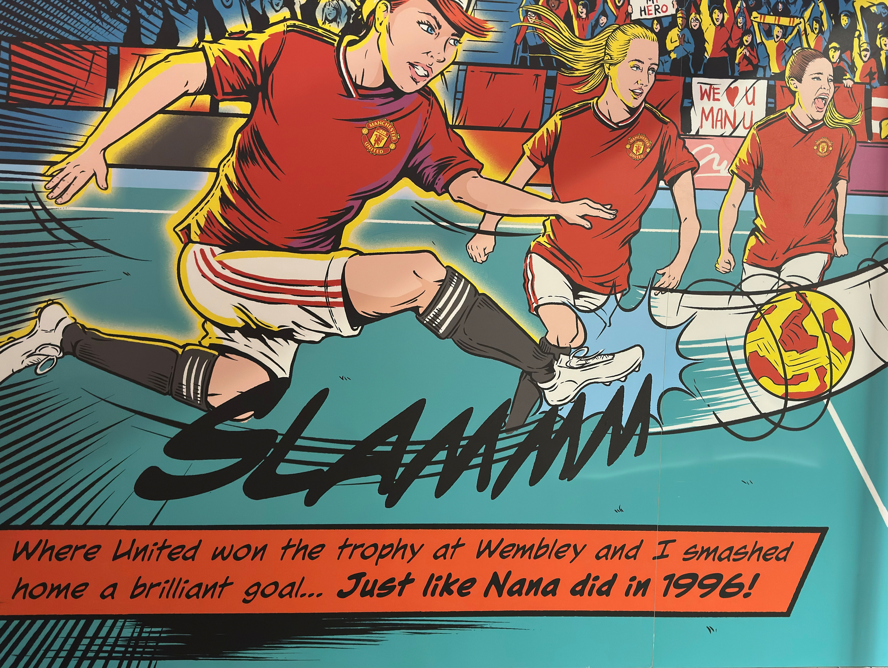 A comic-style illustration showing football players in Manchester United colours about to kick a ball, surrounded by cheering spectators. The caption reads: When United won the trophy at Wembley and I smashed home a brilliant goal… Just like Nana did in 1996!