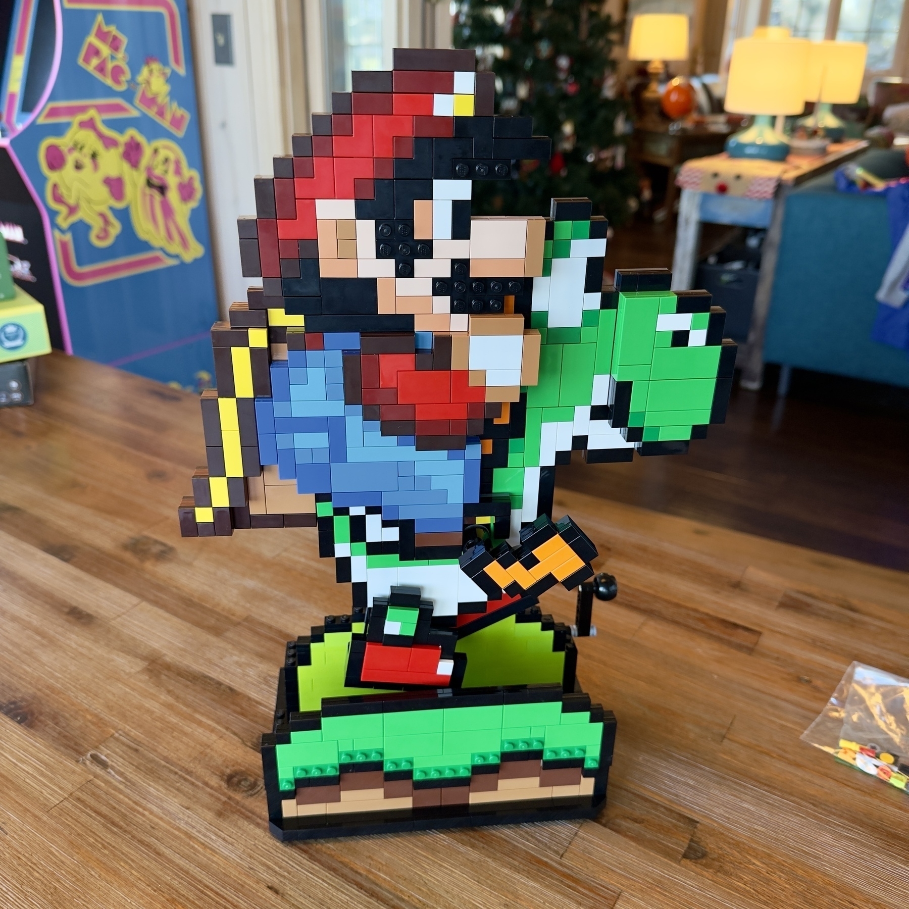 Auto-generated description: A pixelated Lego sculpture depicts a classic video game character riding a green companion, set in a colorful indoor environment.