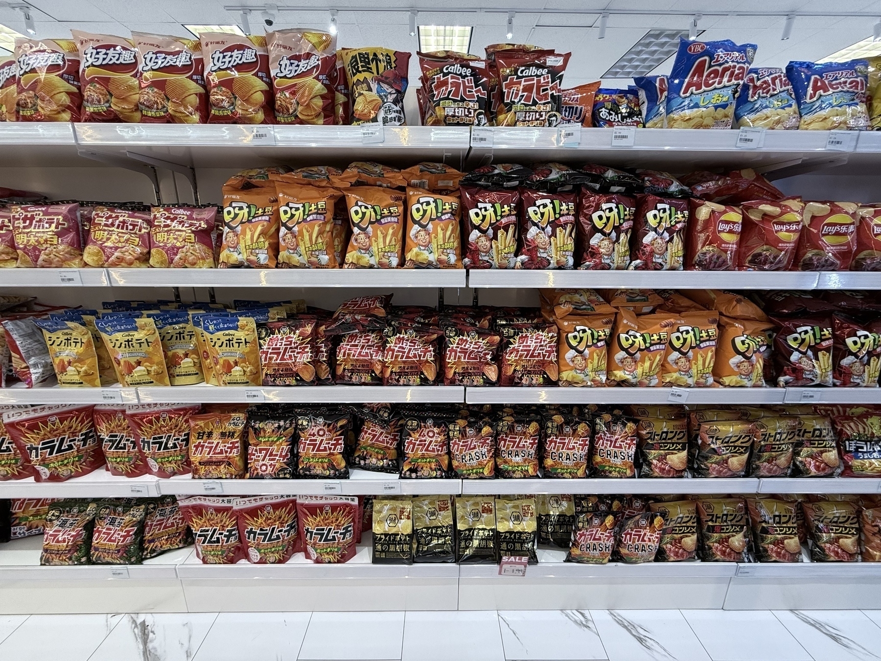 Auto-generated description: A supermarket shelf displays a variety of packaged snacks in colorful bags.